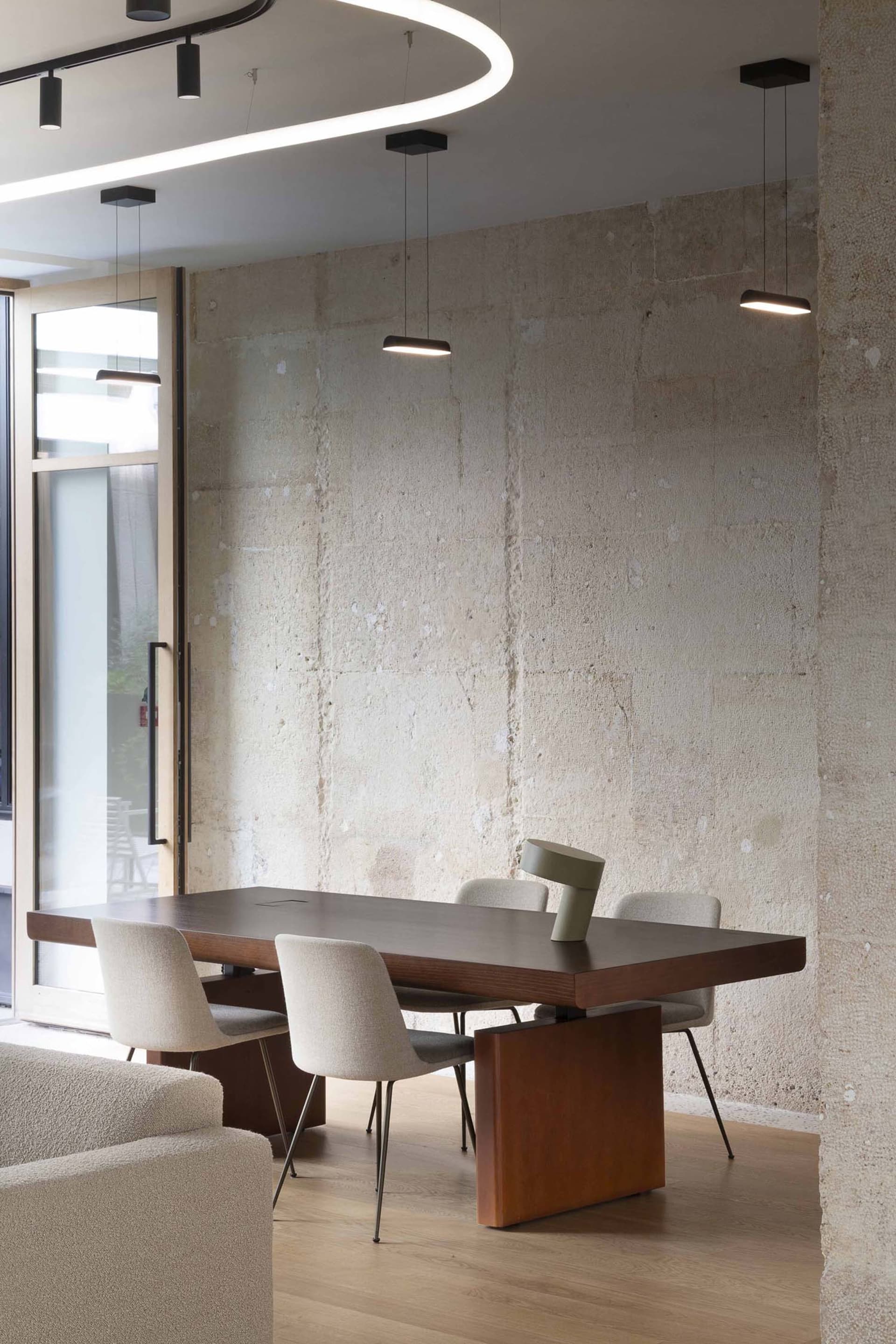 A modern office setting featuring a wooden table with minimalist chairs.