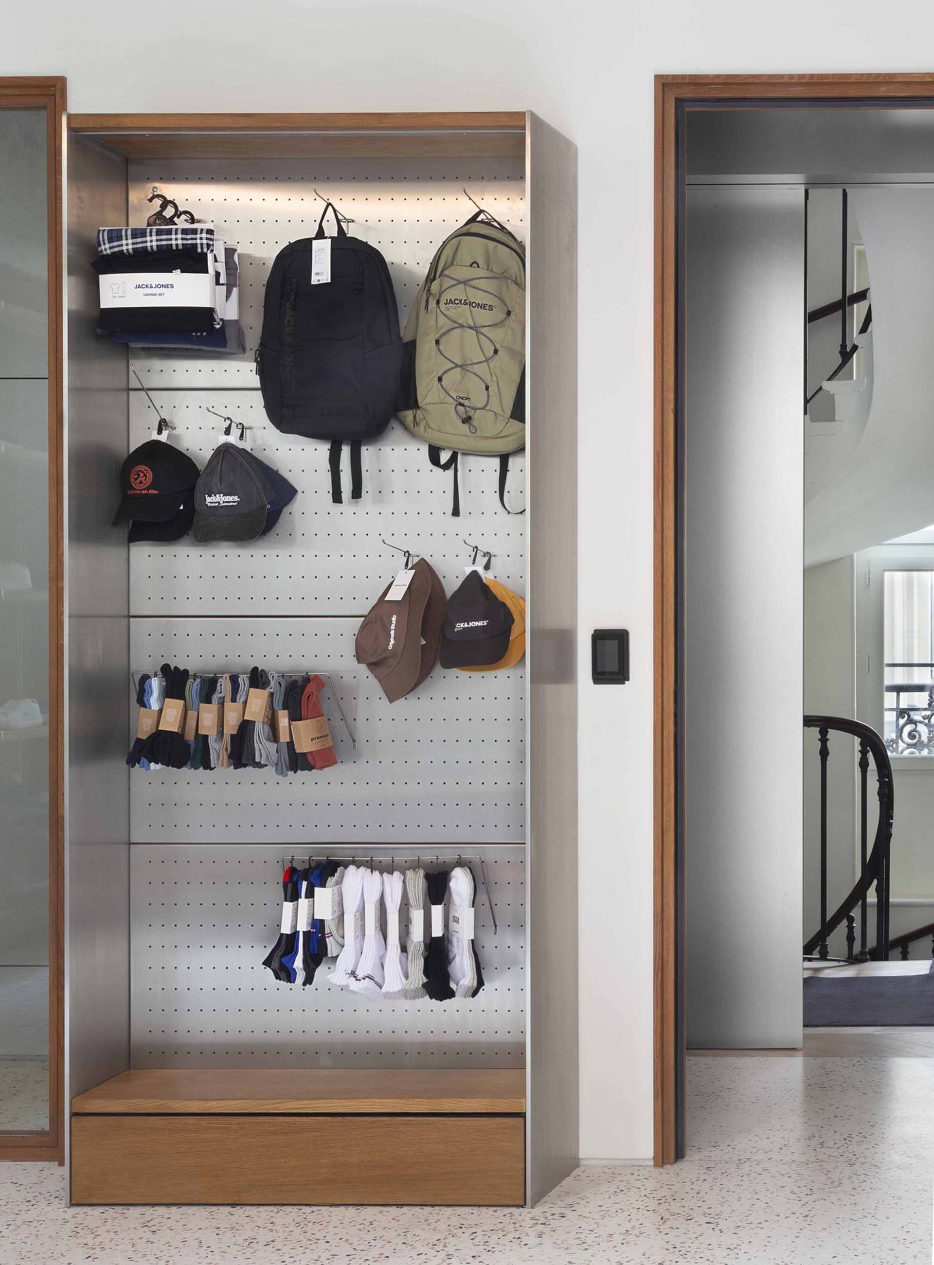 A modern retail display featuring metal shelving and stone finishes with a variety of products such as backpacks, socks, and