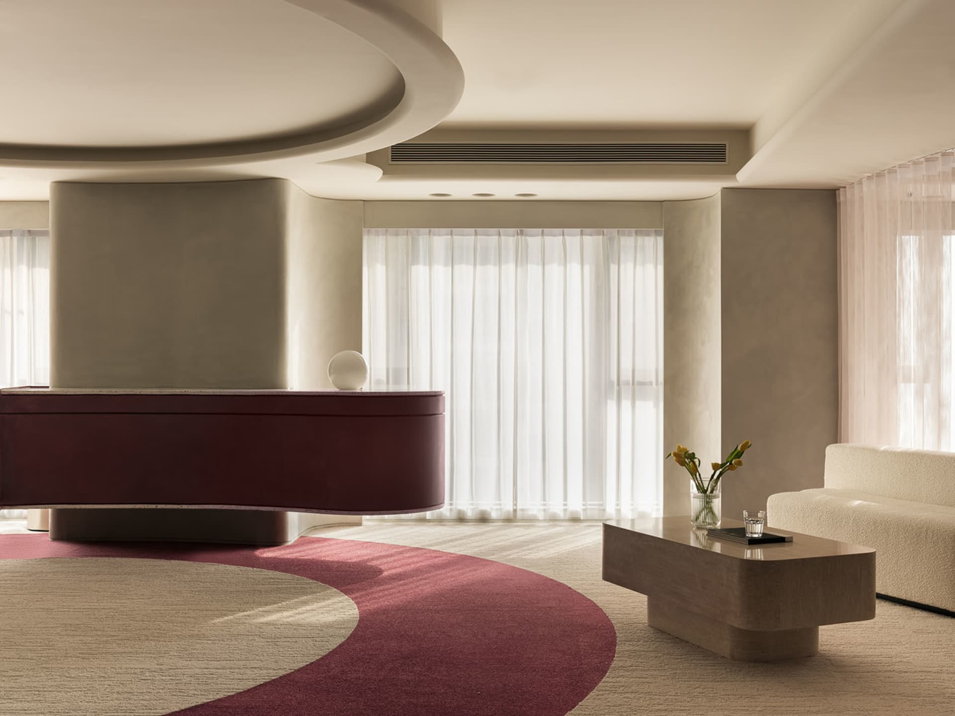 Modern living room with a minimalist design featuring a concrete coffee table and a curved red carpet.