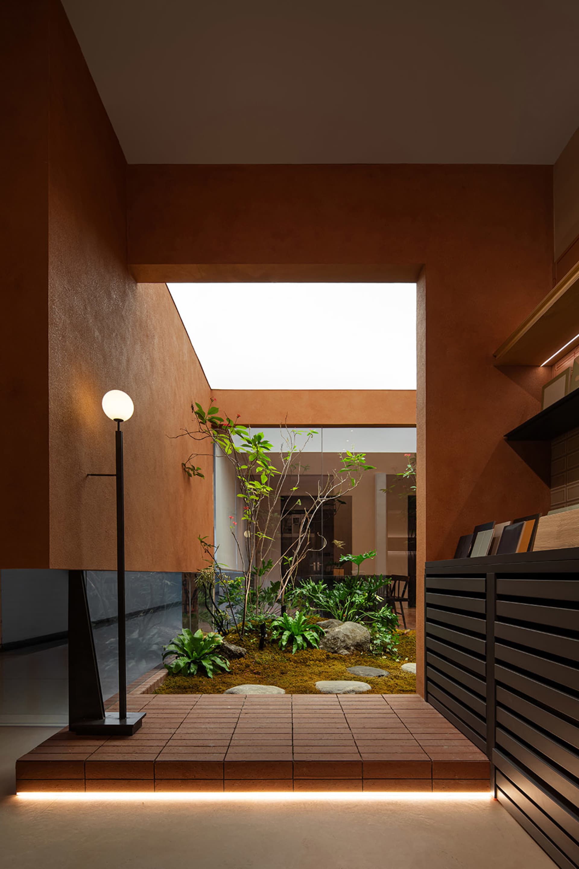 Modern minimalist residential space featuring concrete, wooden elements, and greenery incorporated into the design.