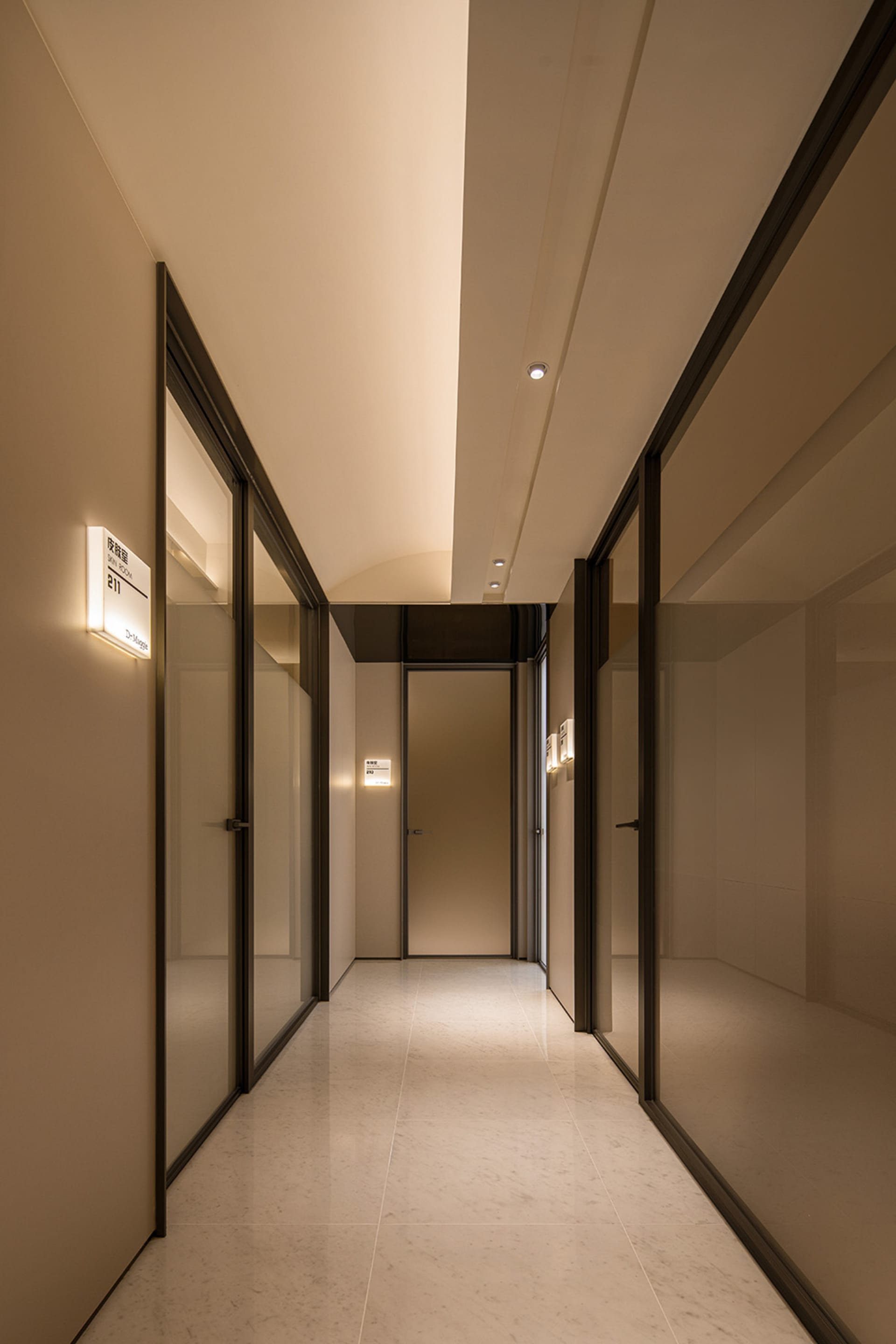 A modern corridor with glass doors and marble flooring.