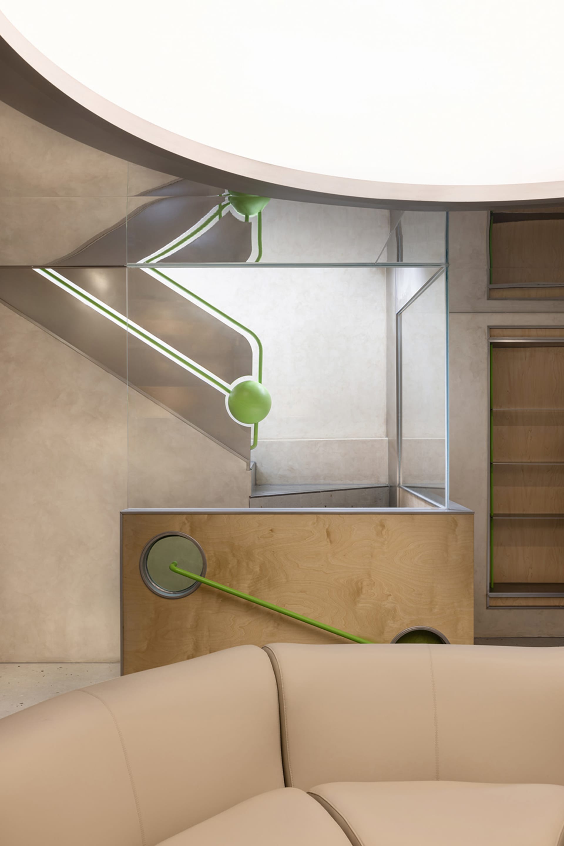 Modern interior space featuring modern concrete staircase with green accents and glass walls.