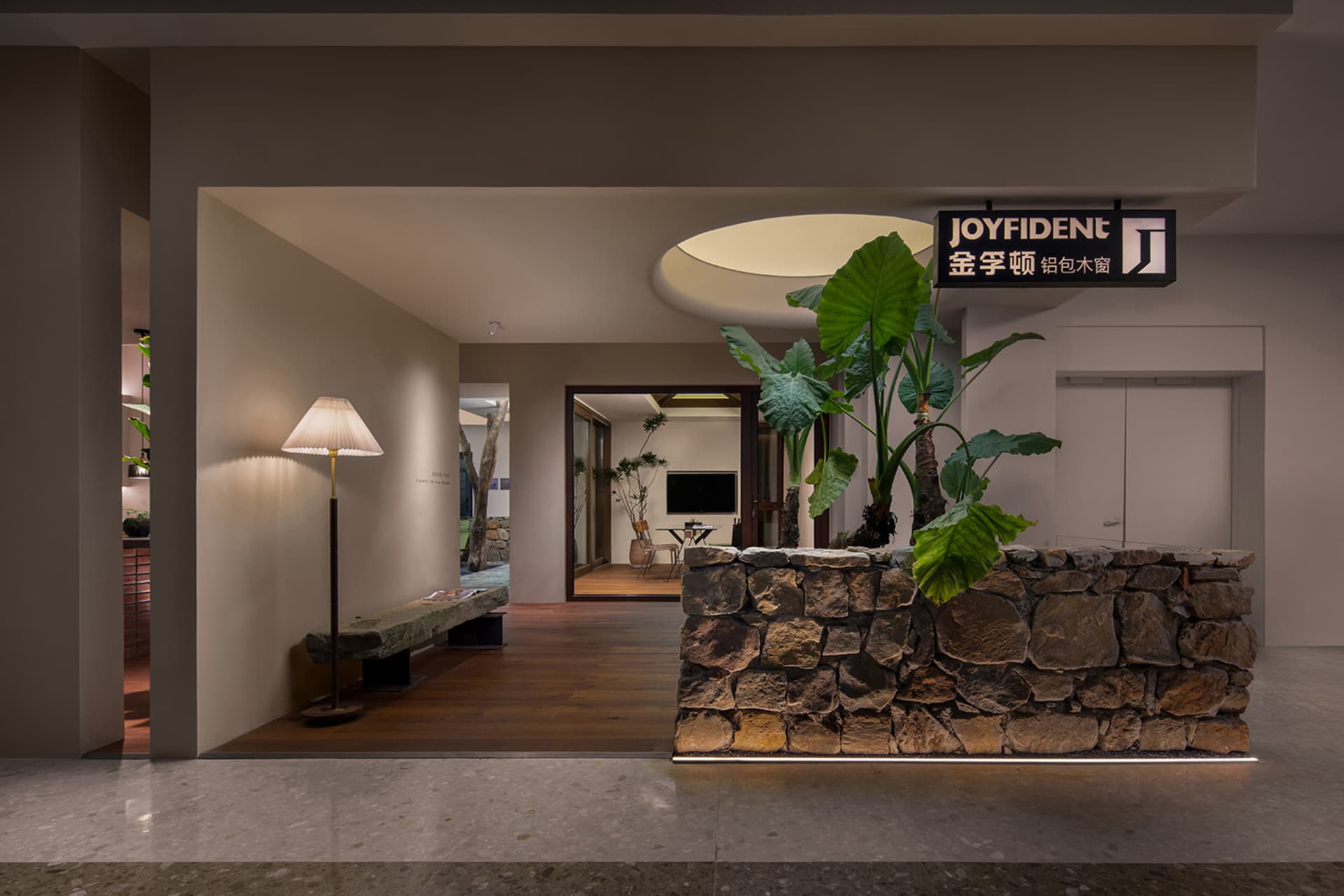 A modern reception desk made of stone with a large plant in front of it.