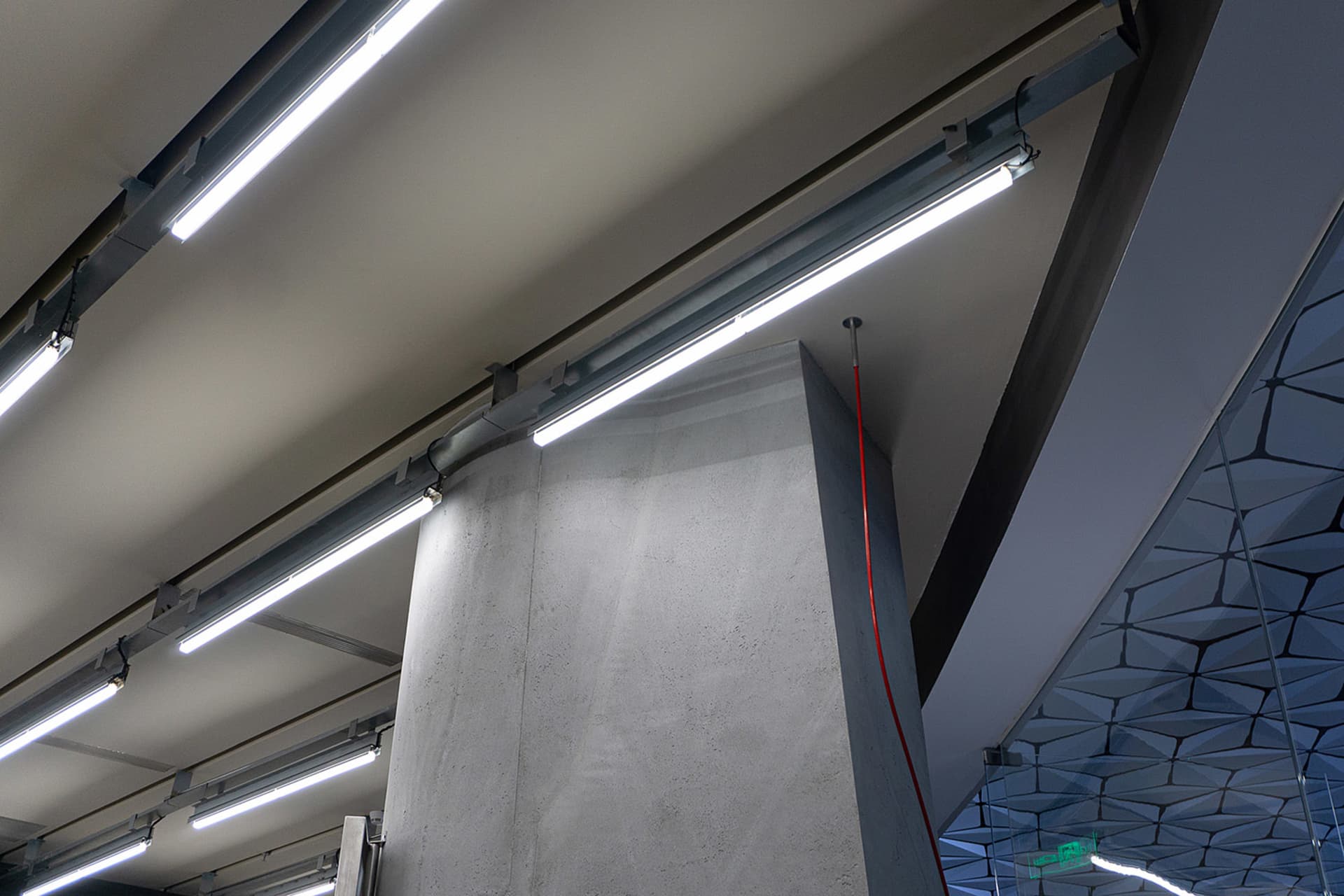 A modern office with concrete ceiling lights and beams, featuring a sleek design.