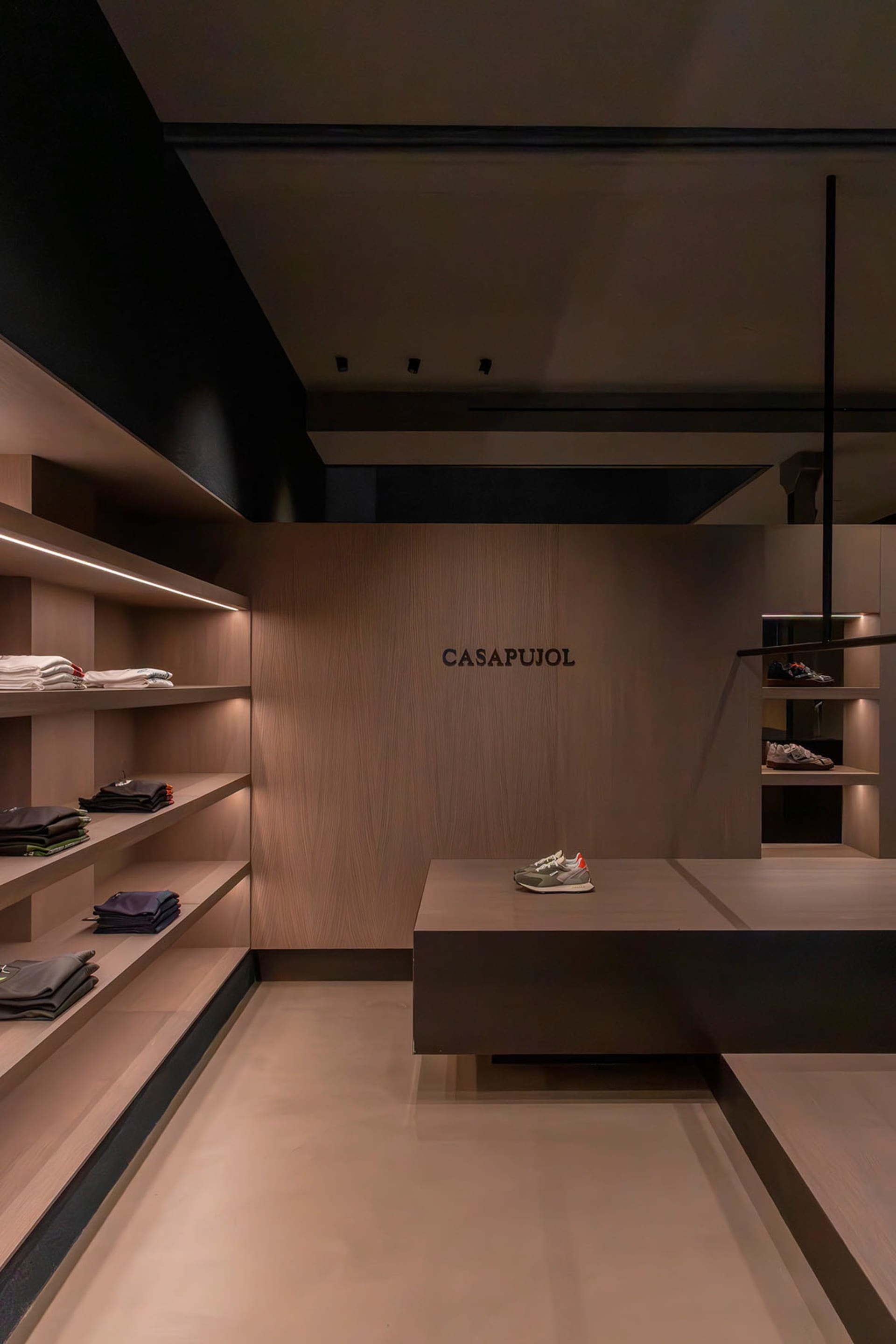 A minimalist fashion retail store featuring wooden shelves and minimalist design elements.