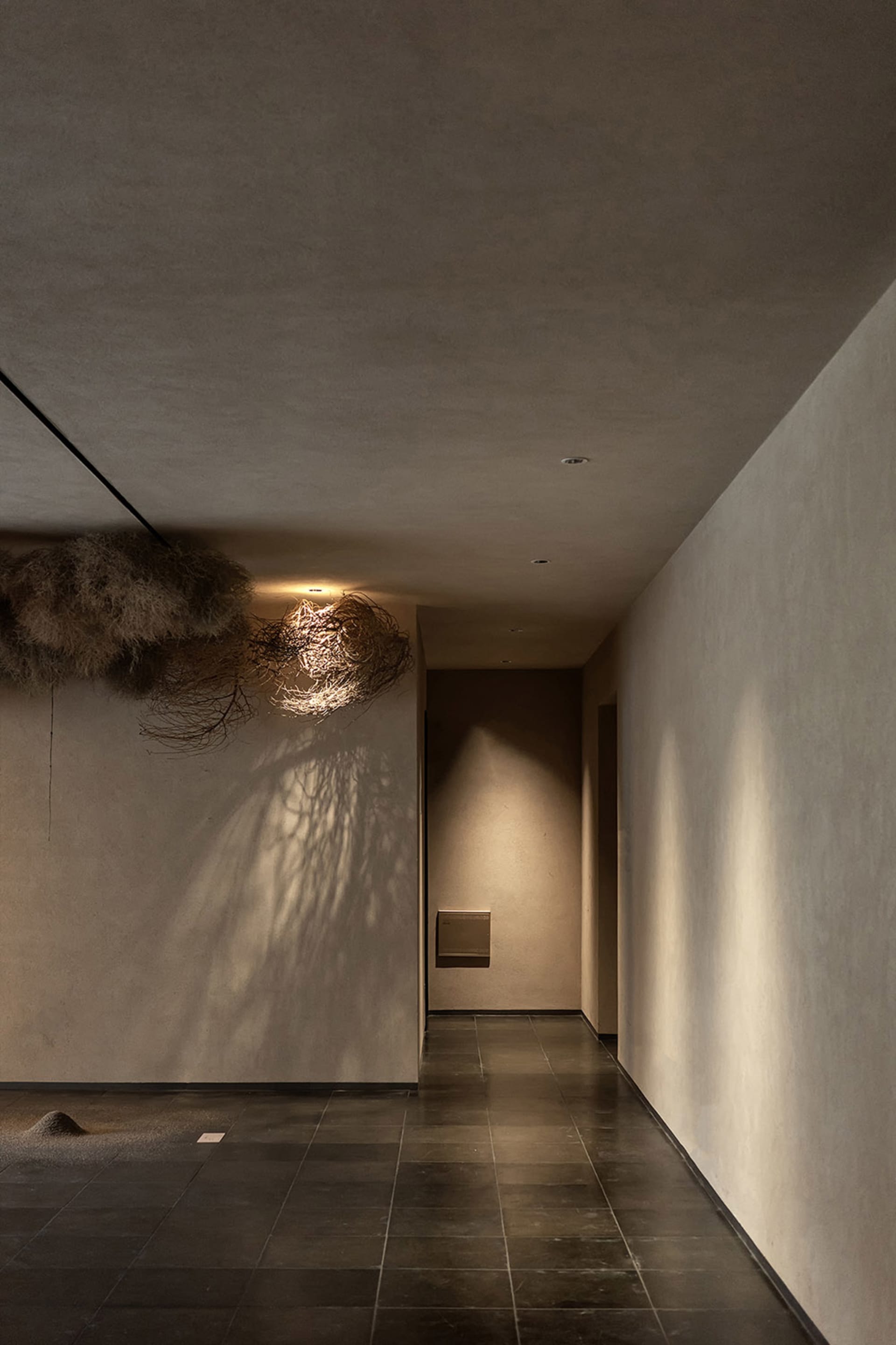 Fabric lighting fixture in a corridor with concrete walls and floor tiles.