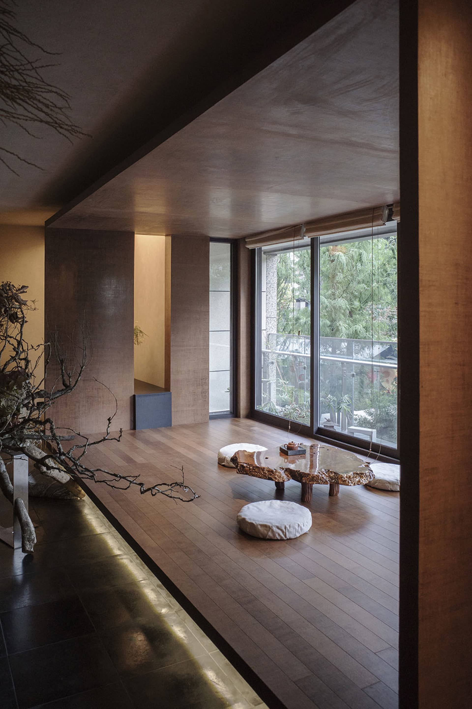 A modern living room with a wooden floor, a tree trunk table, and white cushions.