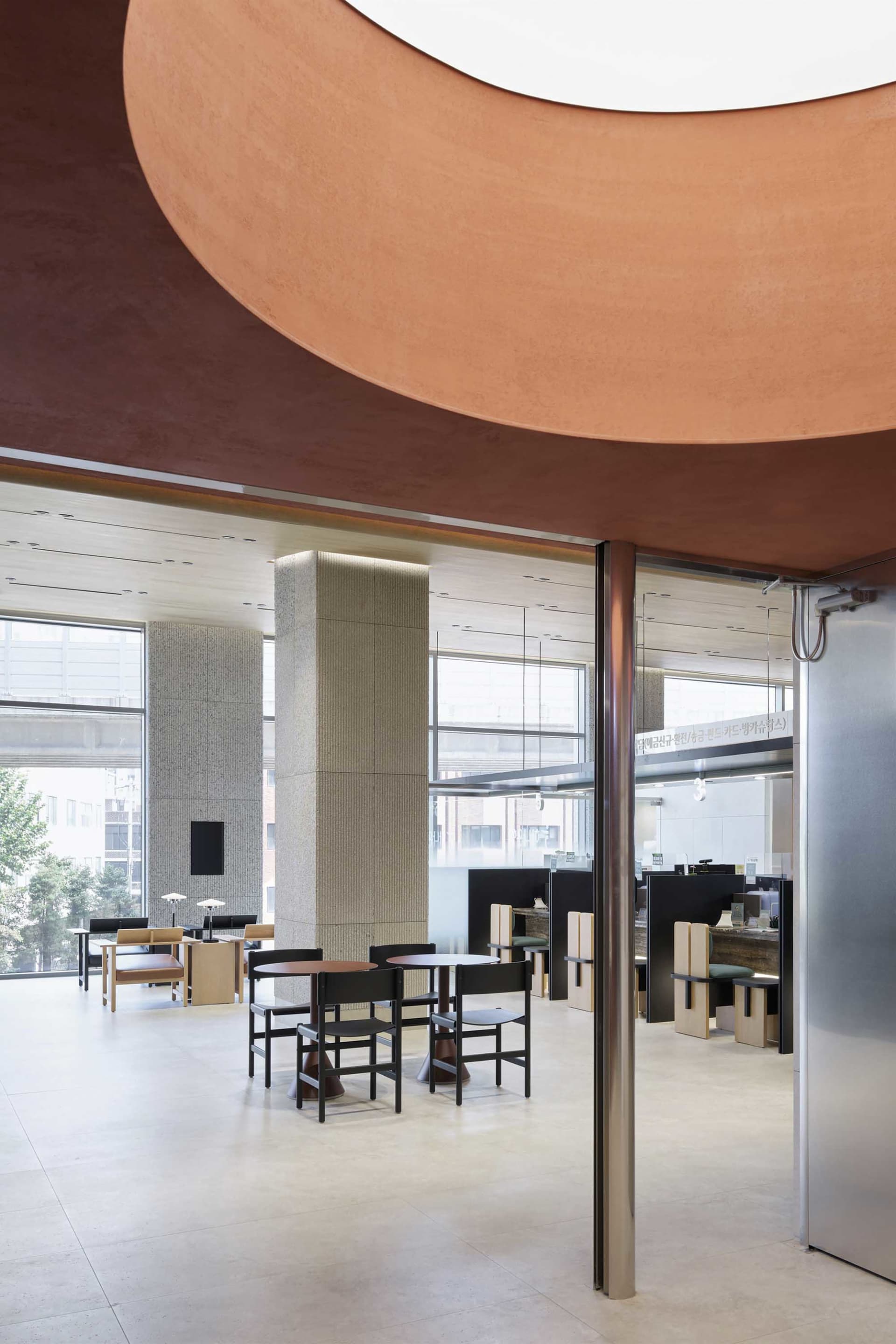 A modern office space featuring concrete, glass, and metal materials in an office lounge area.