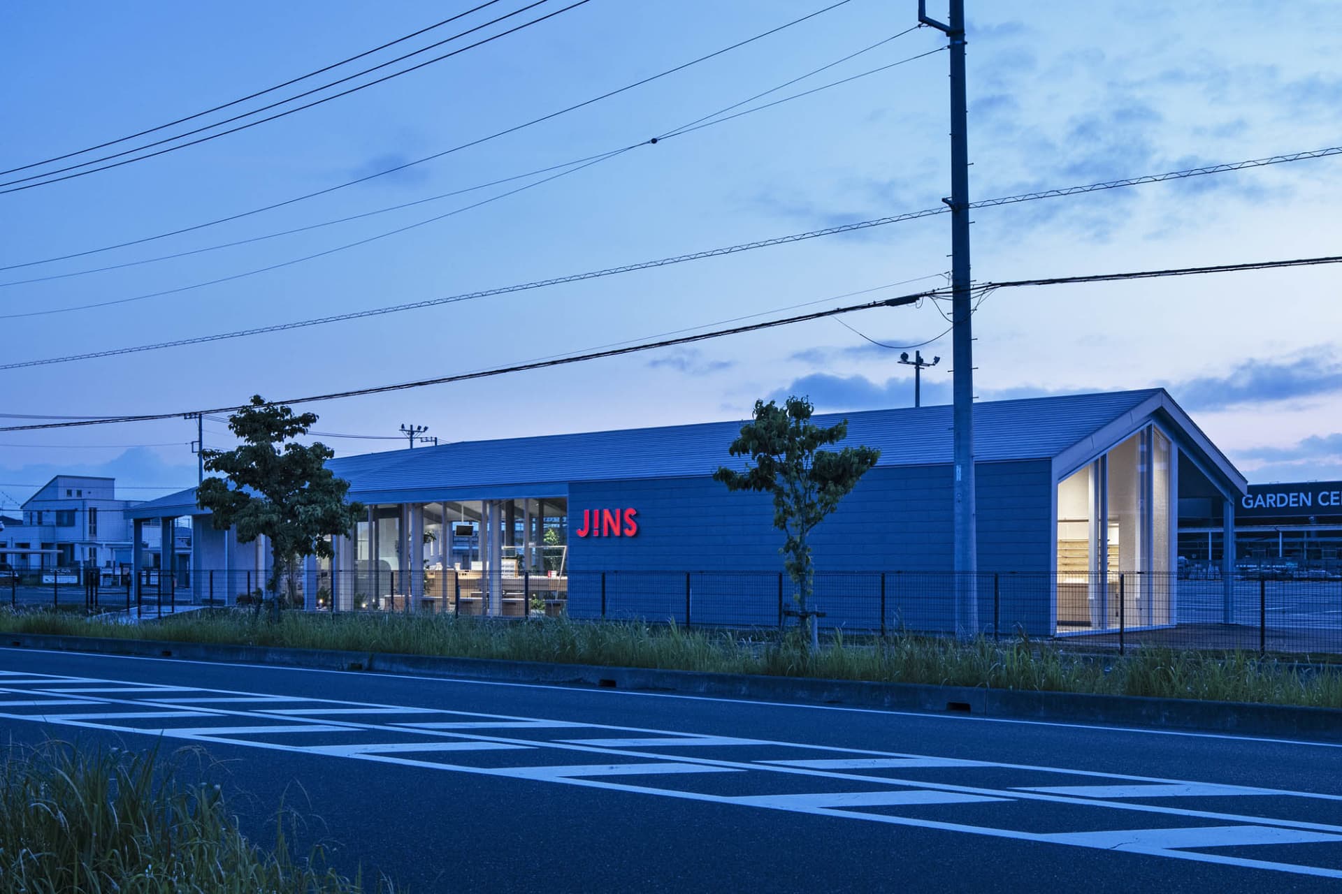 Modern storefront with blue metal cladding, featuring large glass windows and a prominent signage.
