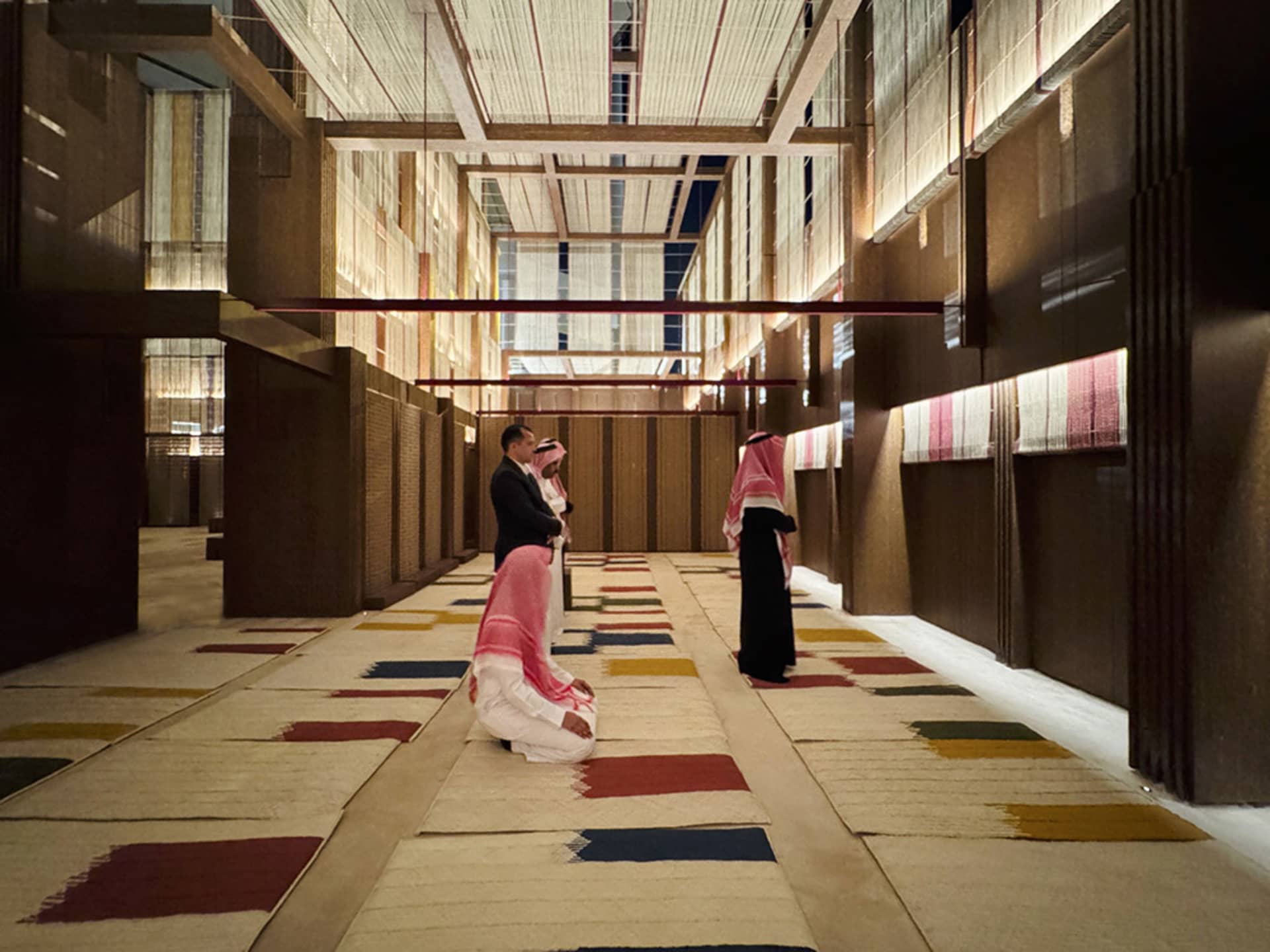 A modern hallway with colorful carpet tiles and a high ceiling with exposed beams.