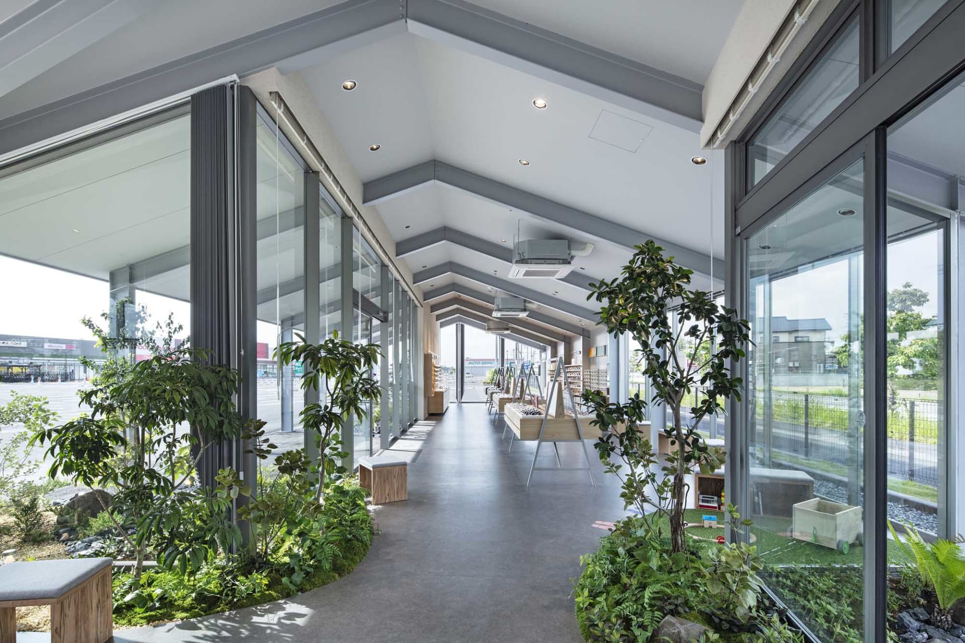 Modern interior of a coffee shop featuring concrete flooring and green plants.