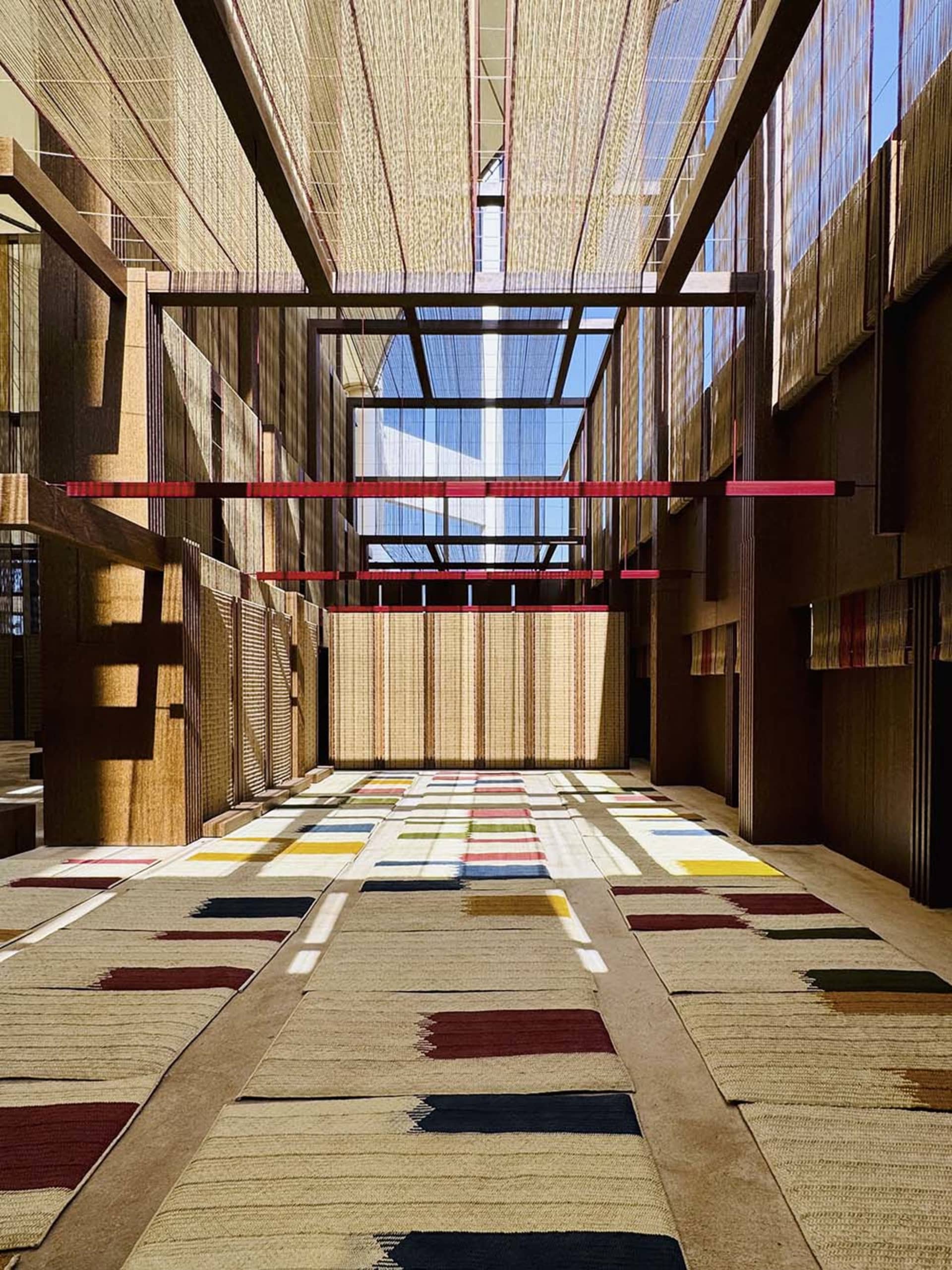 A modern corridor with colorful floor tiles, wooden walls, and concrete flooring under a skylight with natural light streamin