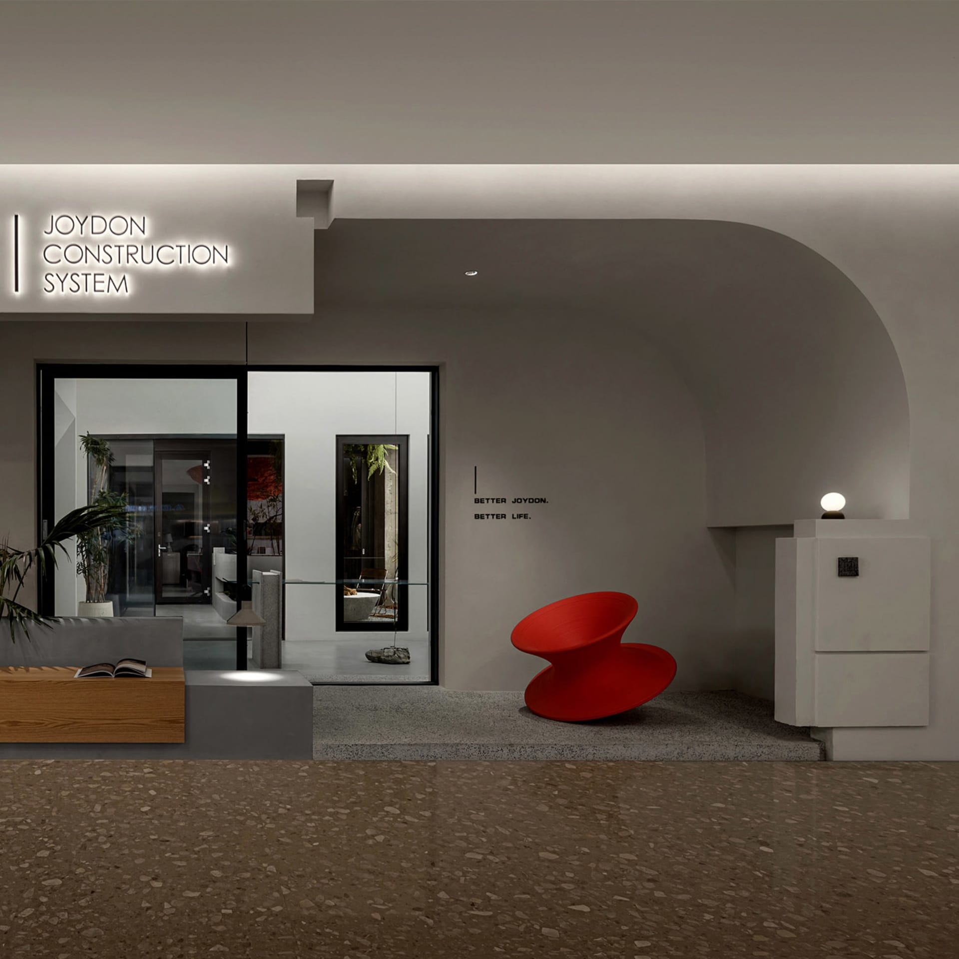 Modern minimalist lobby with white walls, glass doors, a red sculptural chair, and concrete flooring.