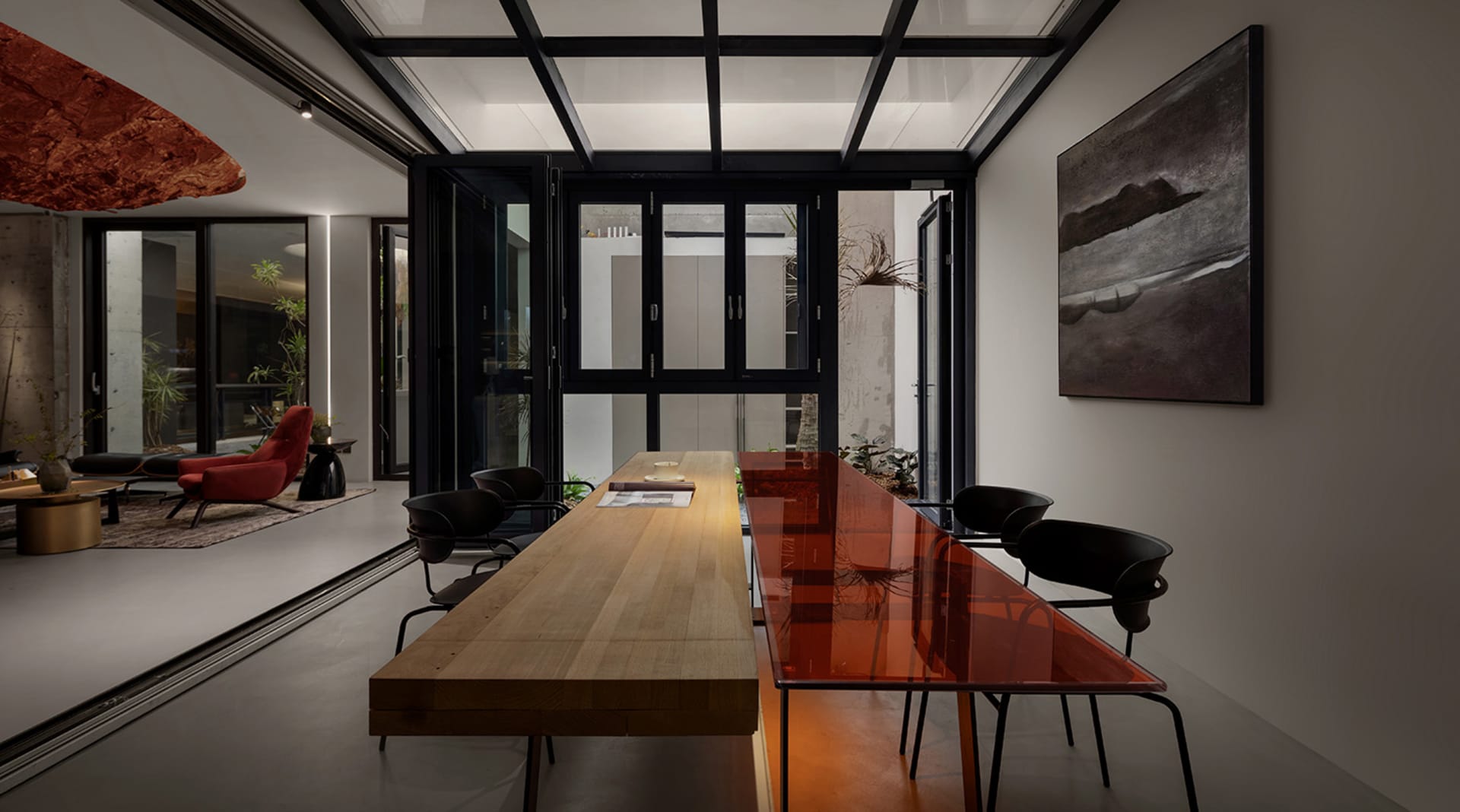 Modern dining room featuring minimalist design, wooden table, glass and metal chairs, and large painting.