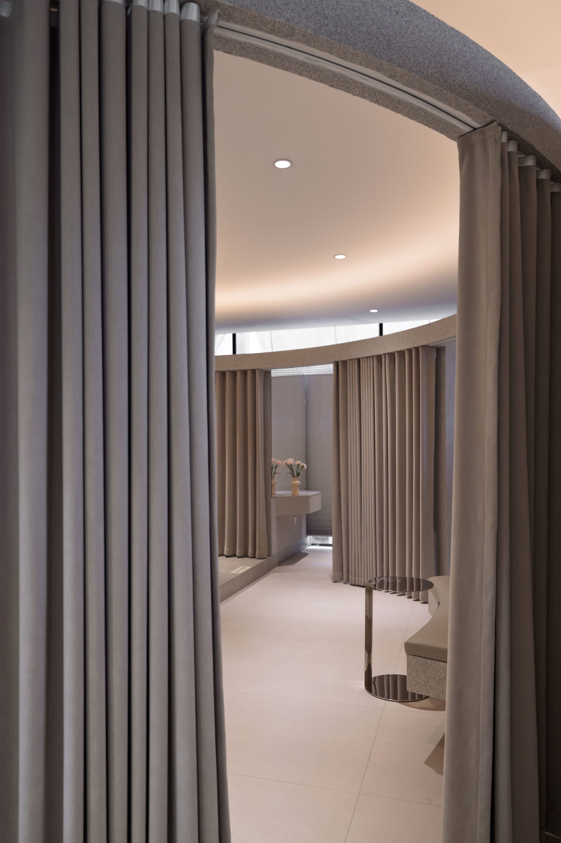 A serene spa interior featuring concrete flooring and light-colored curtains.