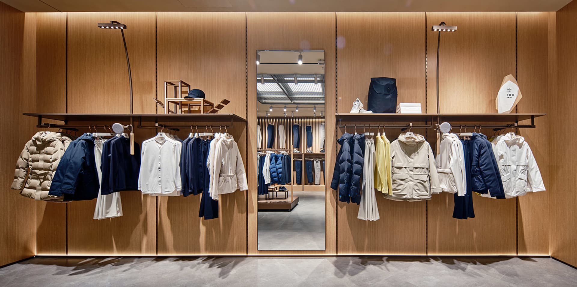 Retail shop featuring clothing displayed on wooden shelves and racks with a warm, minimalist design.