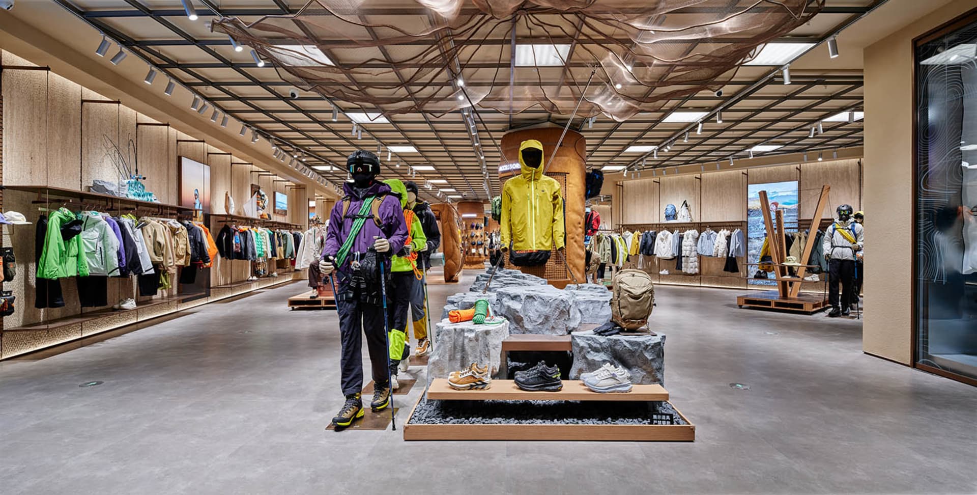A retail store showcasing sportswear and accessories, with mannequins dressed in outdoor gear, and shelves filled with clothi
