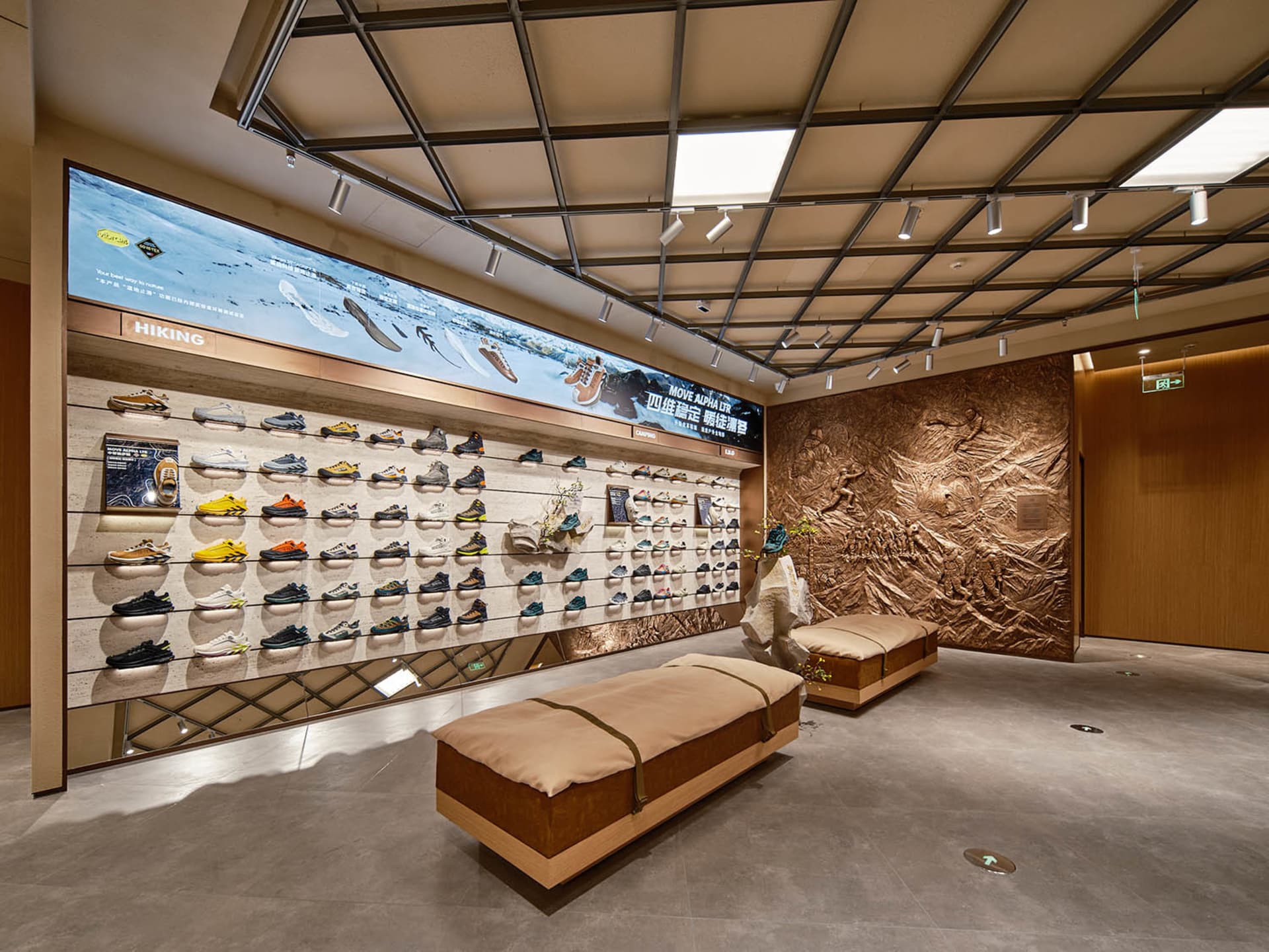 一間鞋店零售空間，牆面展示各式鞋款，搭配木製長椅與大型螢幕播放鞋款系列。