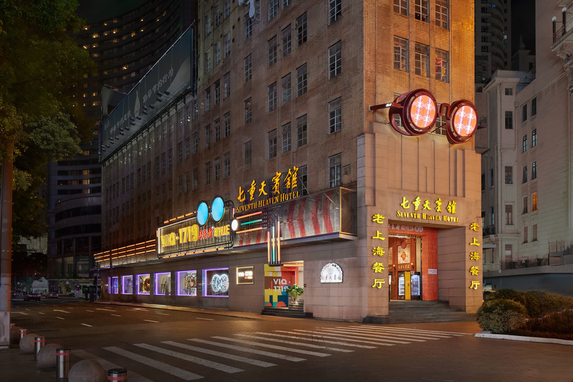 Modern hotel entrance featuring glass, brick, and neon lights.