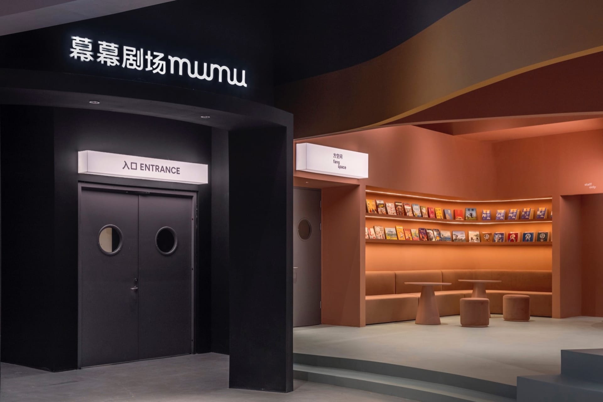 Modern theater entrance with black curved walls and white lighting.