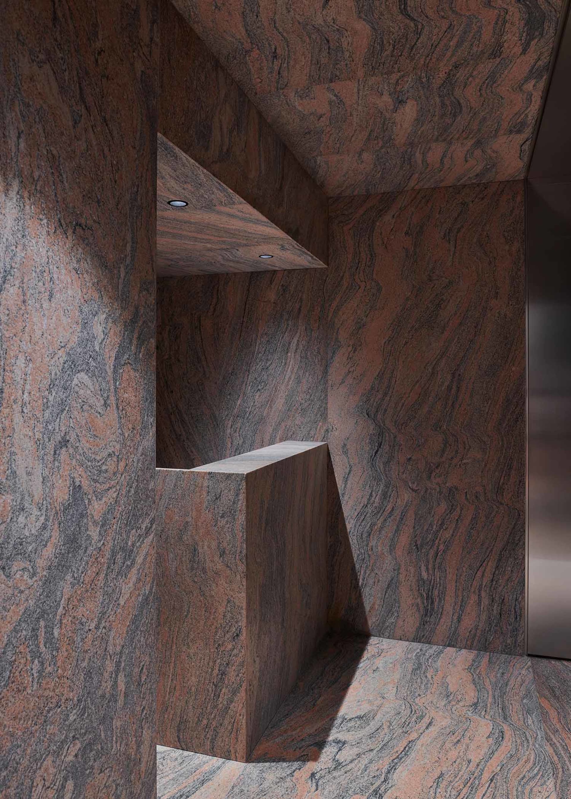 A modern architectural space features tall bronze columns with a swirling design.