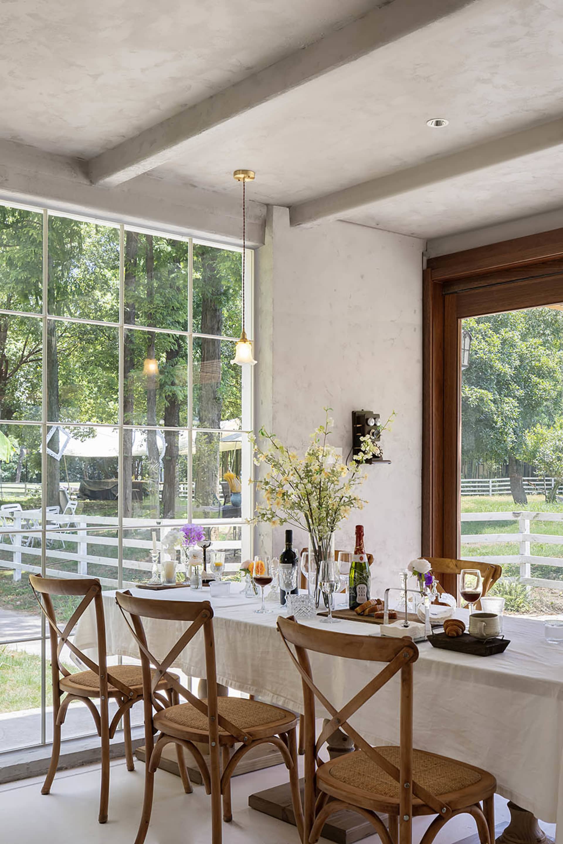 A modern dining room with wooden seating, large windows, and a table set for a meal.