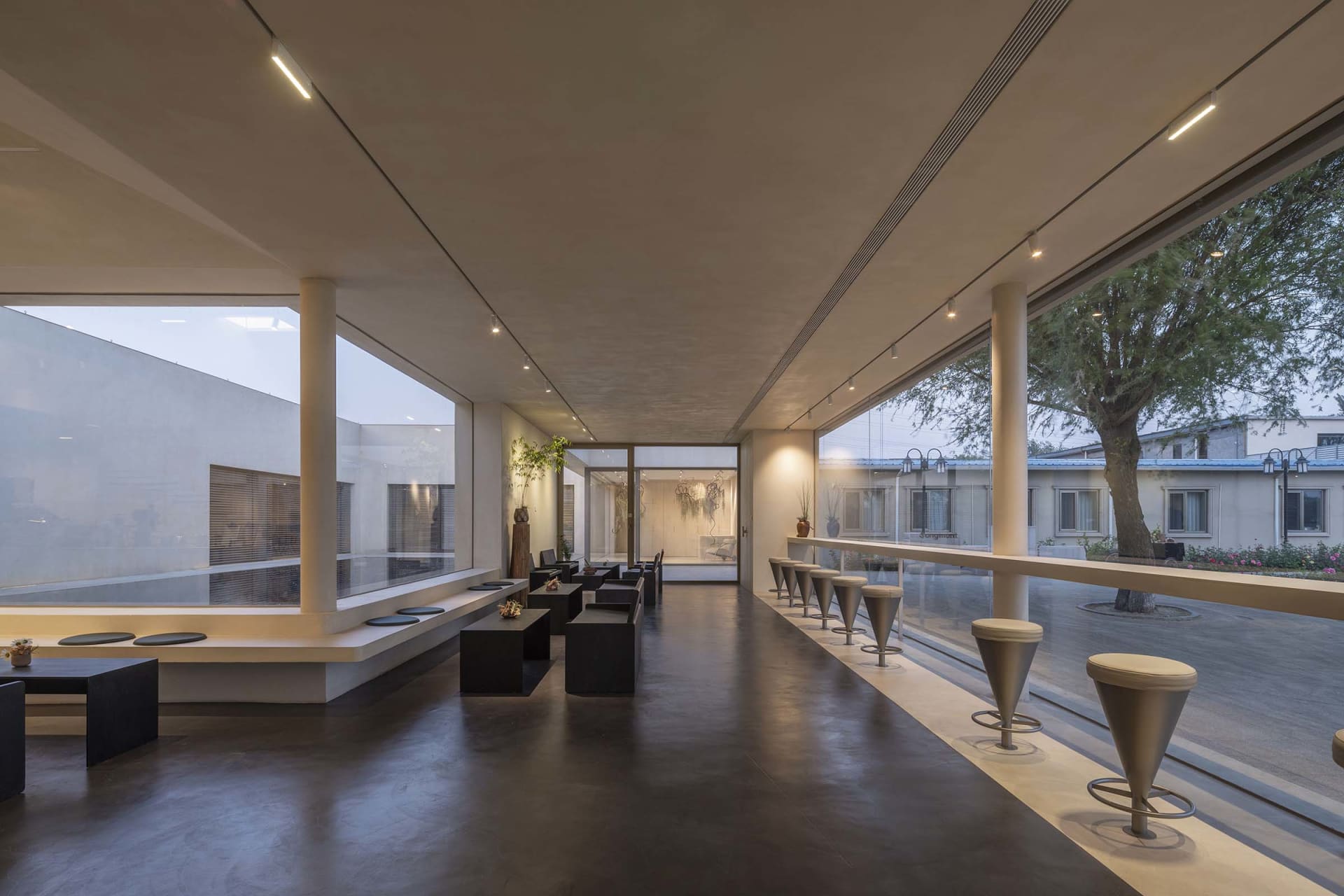 Modern industrial commercial space featuring concrete flooring and large windows.