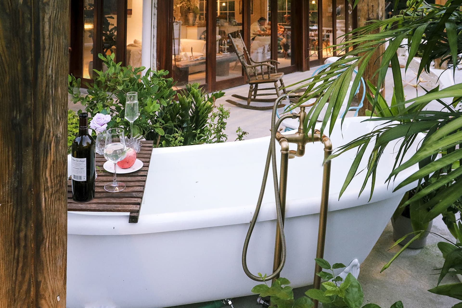 A white ceramic bathtub adorned with green plants and decorative items, set against a backdrop of a cozy indoor space.
