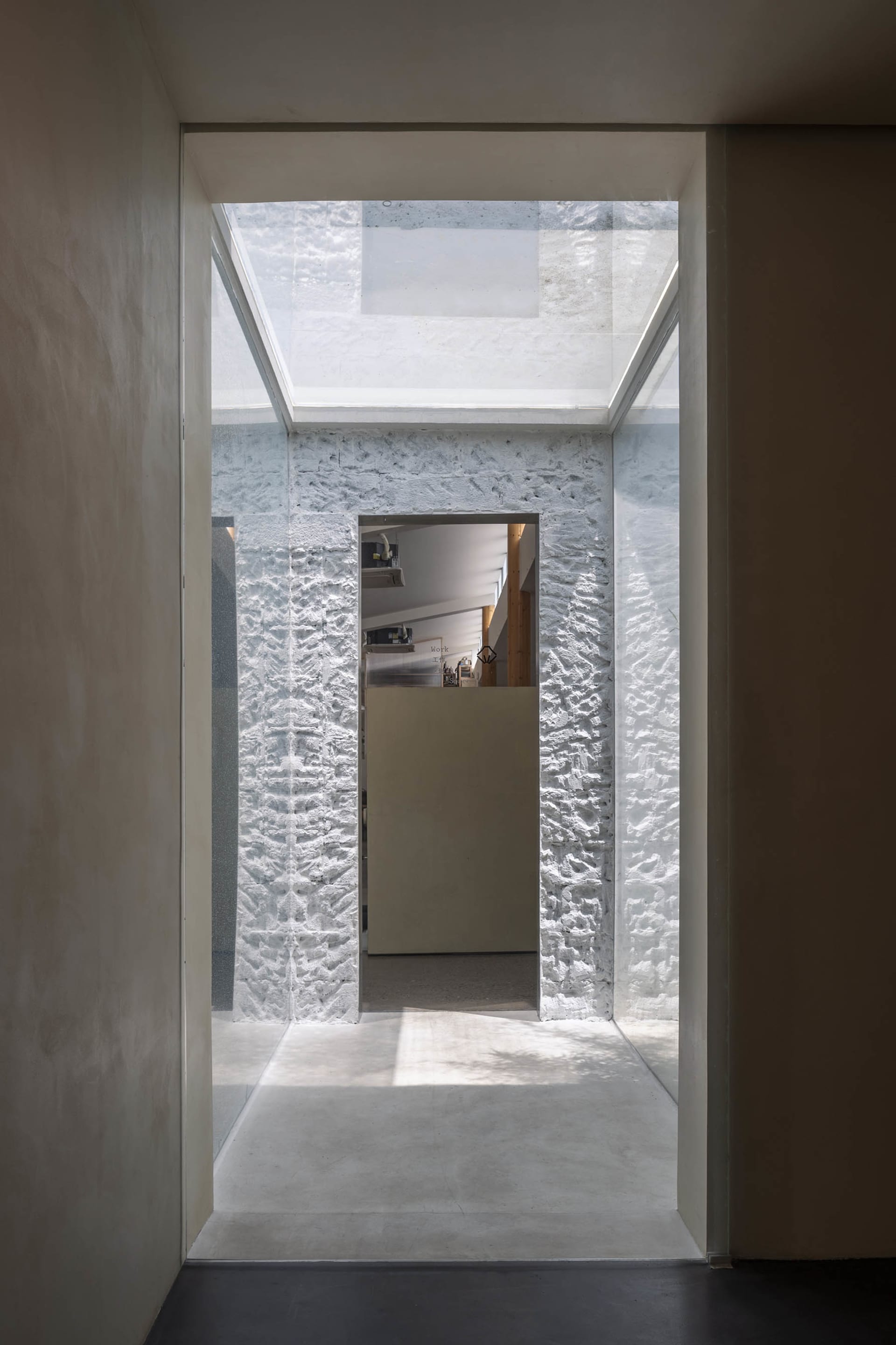 A modern interior space featuring textured concrete walls and a skylight.