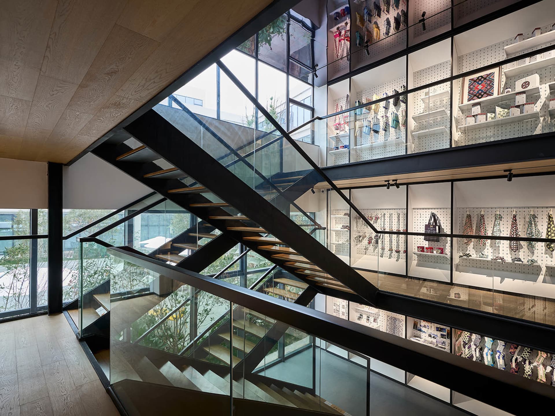 Modern industrial trim store with black metal staircase and glass railing, featuring a variety of products displayed on pegbo