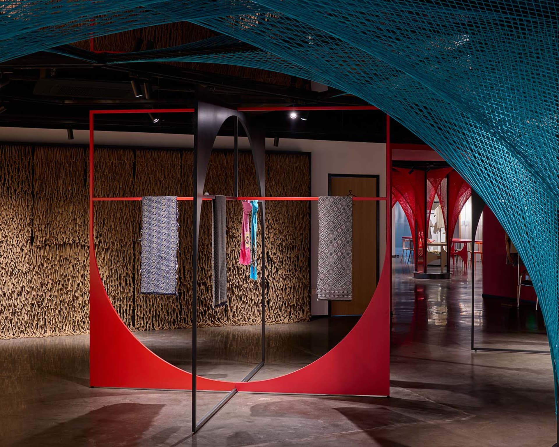 Modern fashion retail space featuring red canvas walls and metal structures.