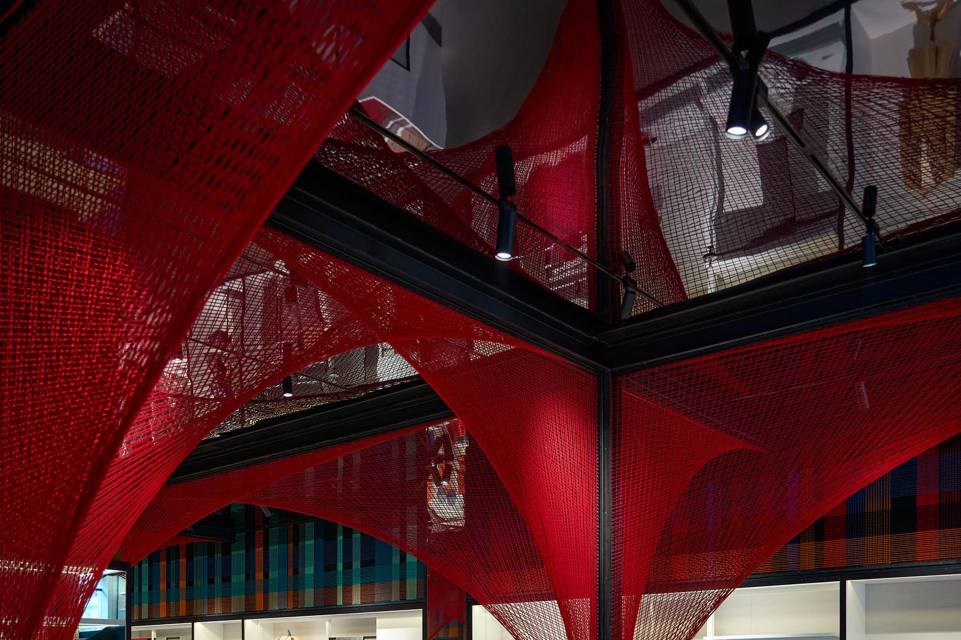 A modern office space featuring a striking installation of metal netting suspended from the ceiling.