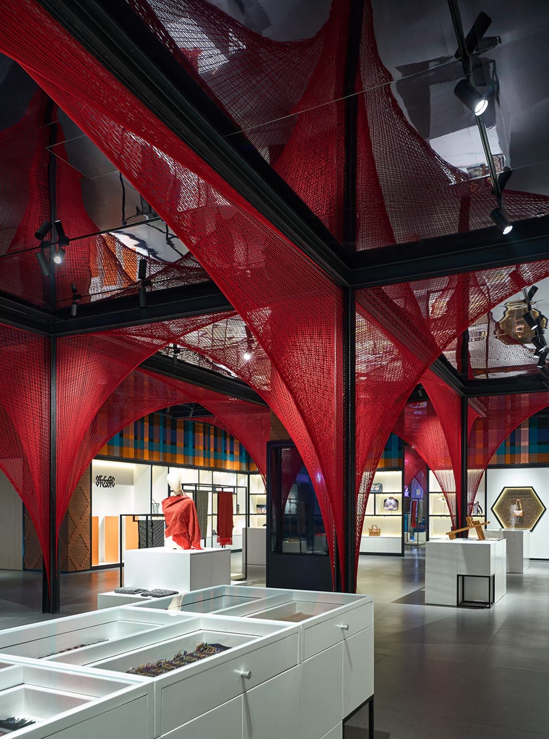 A retail space featuring red tension fabric structures and white display cases.