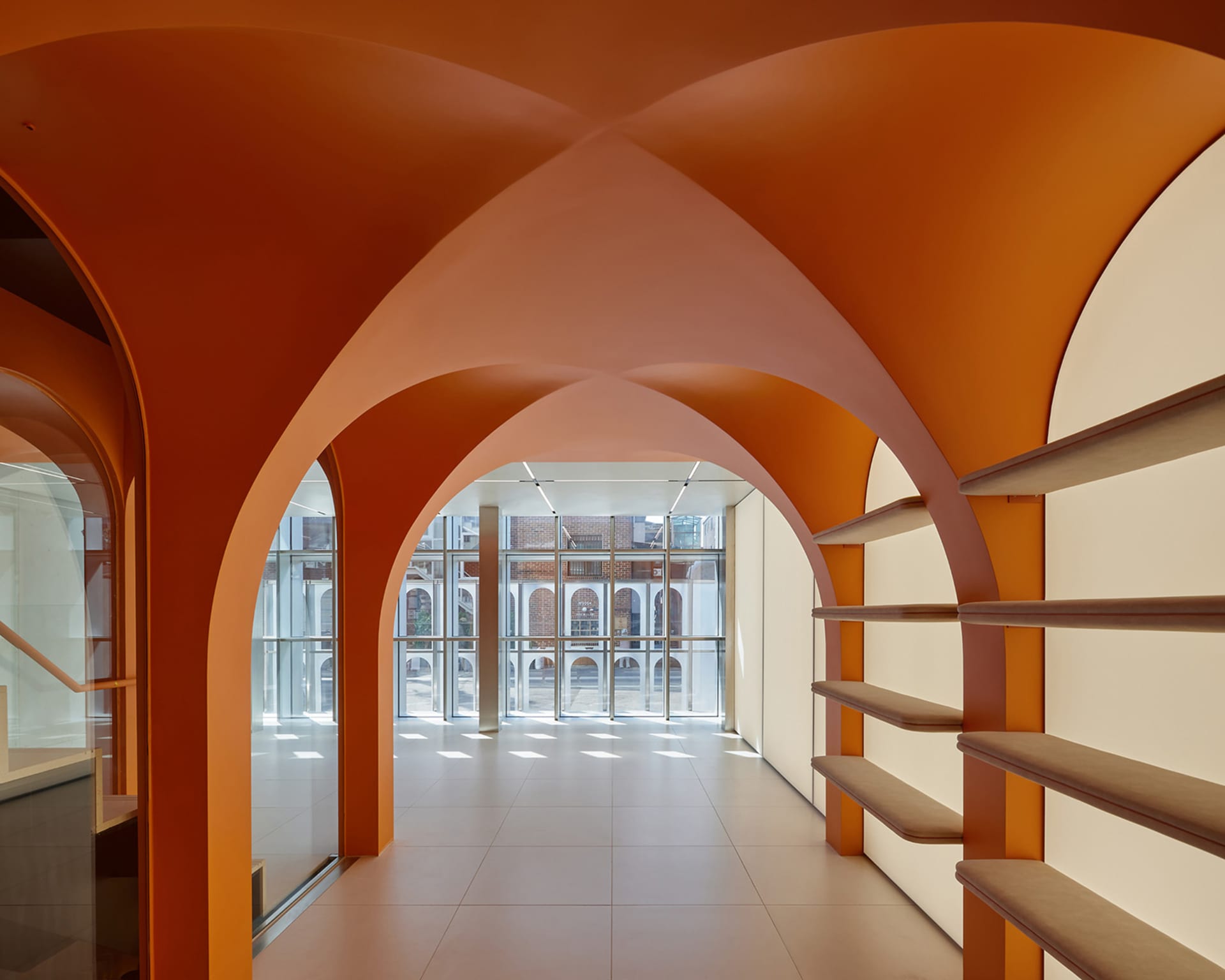 A modern lobby featuring orange concrete arches and shelving units with cushioned benches.