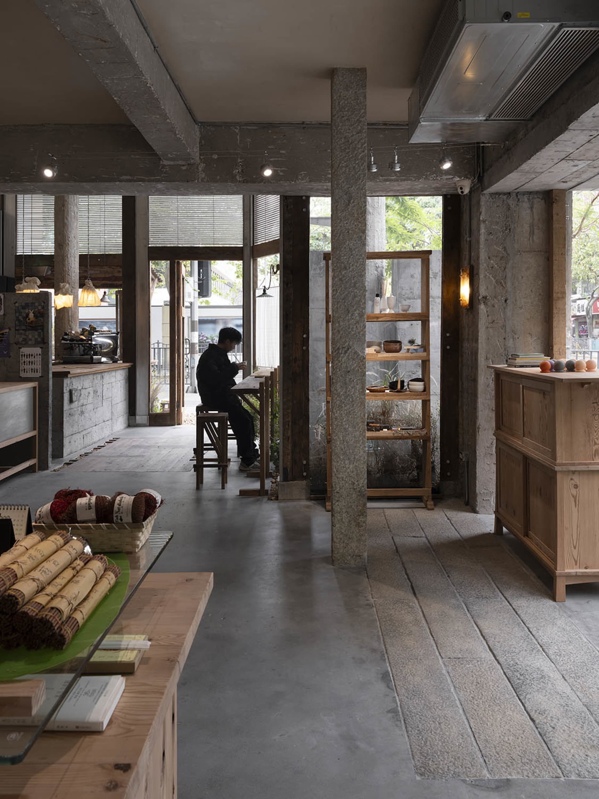 Interior of a coffee shop featuring concrete and wooden materials.