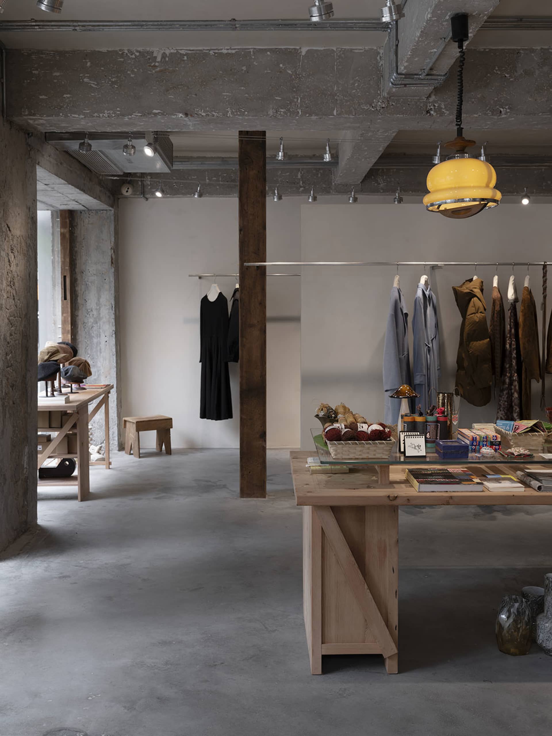 An industrial retail space featuring a wooden display table with various products and clothing items.