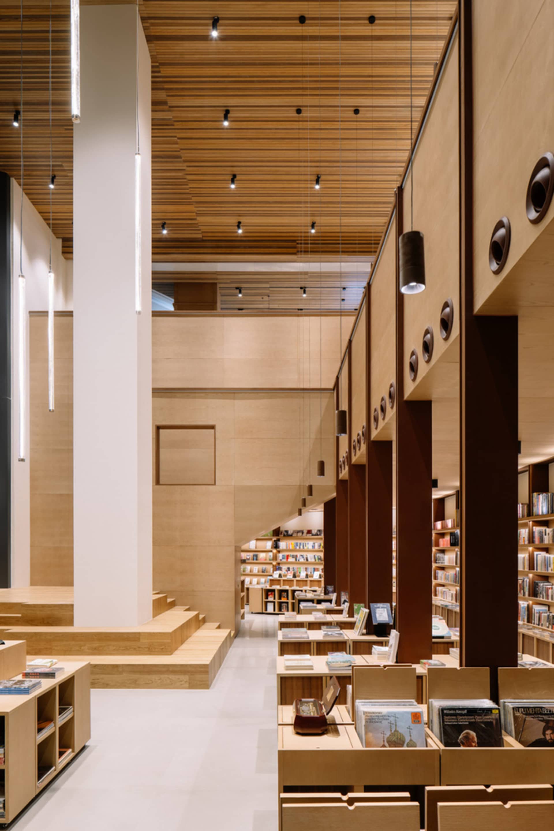 A modern library space with wooden shelves and glass panels.
