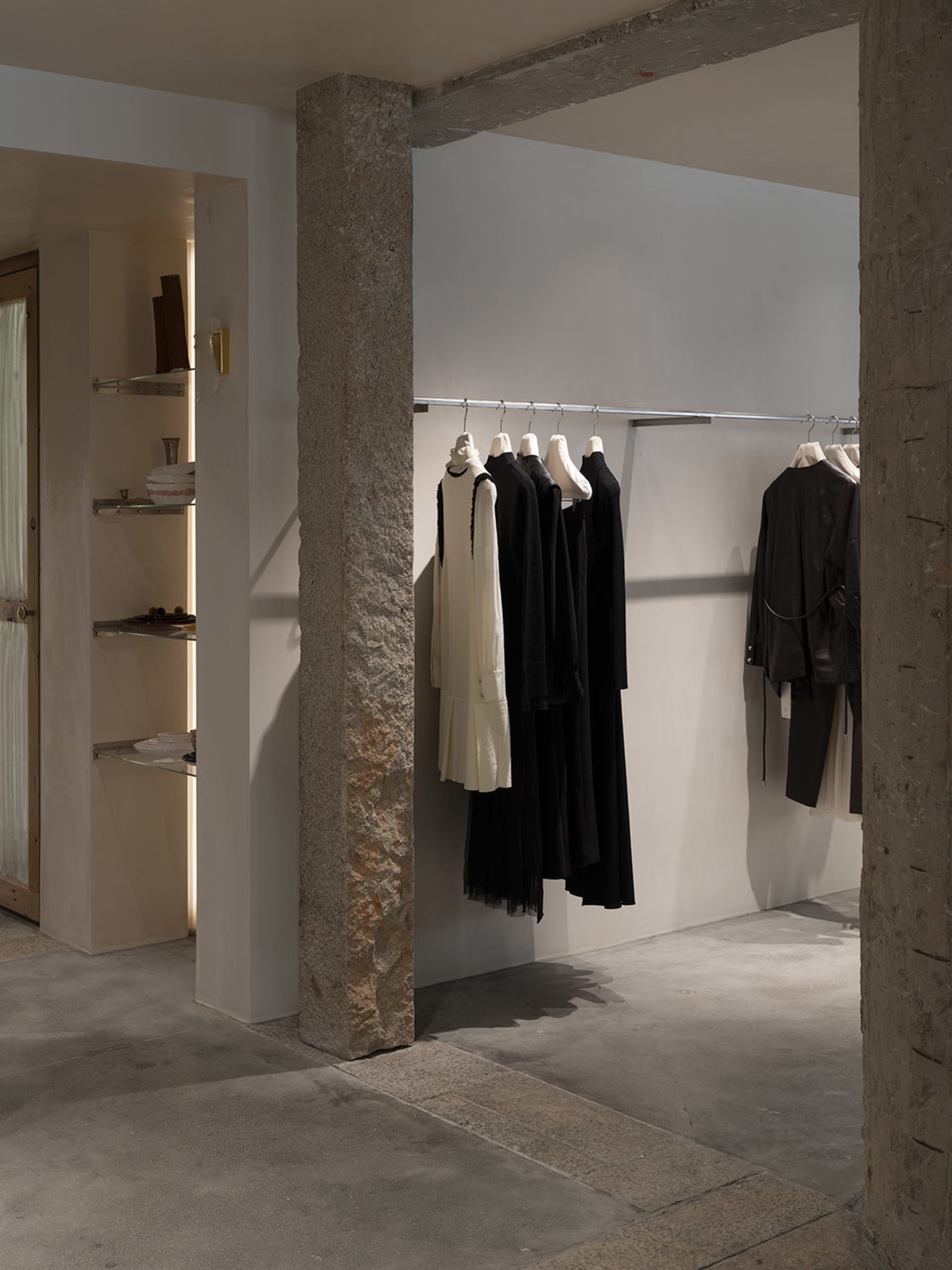 A modern retail store with concrete floors displaying clothing on a hanging rail.