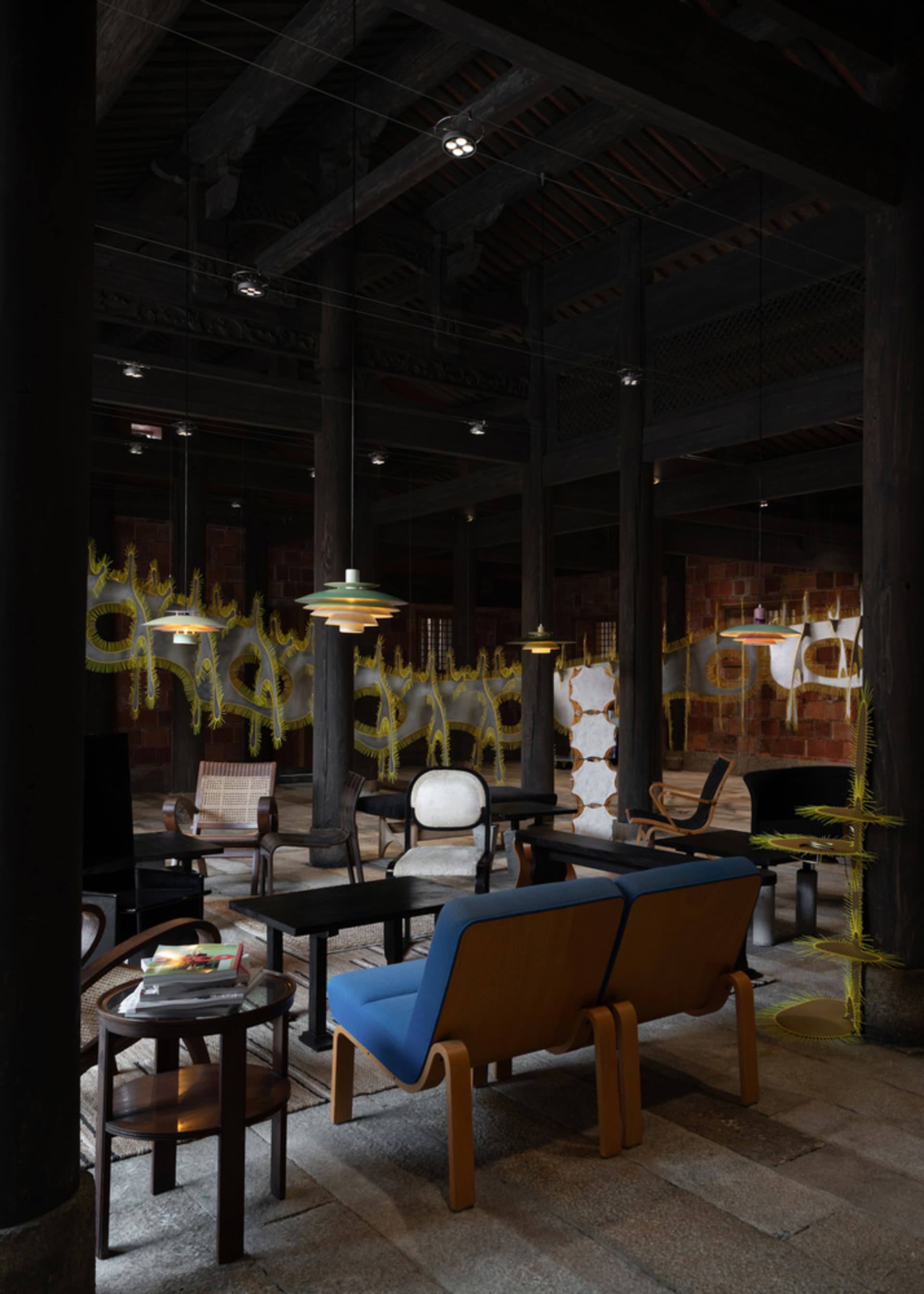 A modern interior living room with wooden furniture, a blue sofa, and hanging lamps.