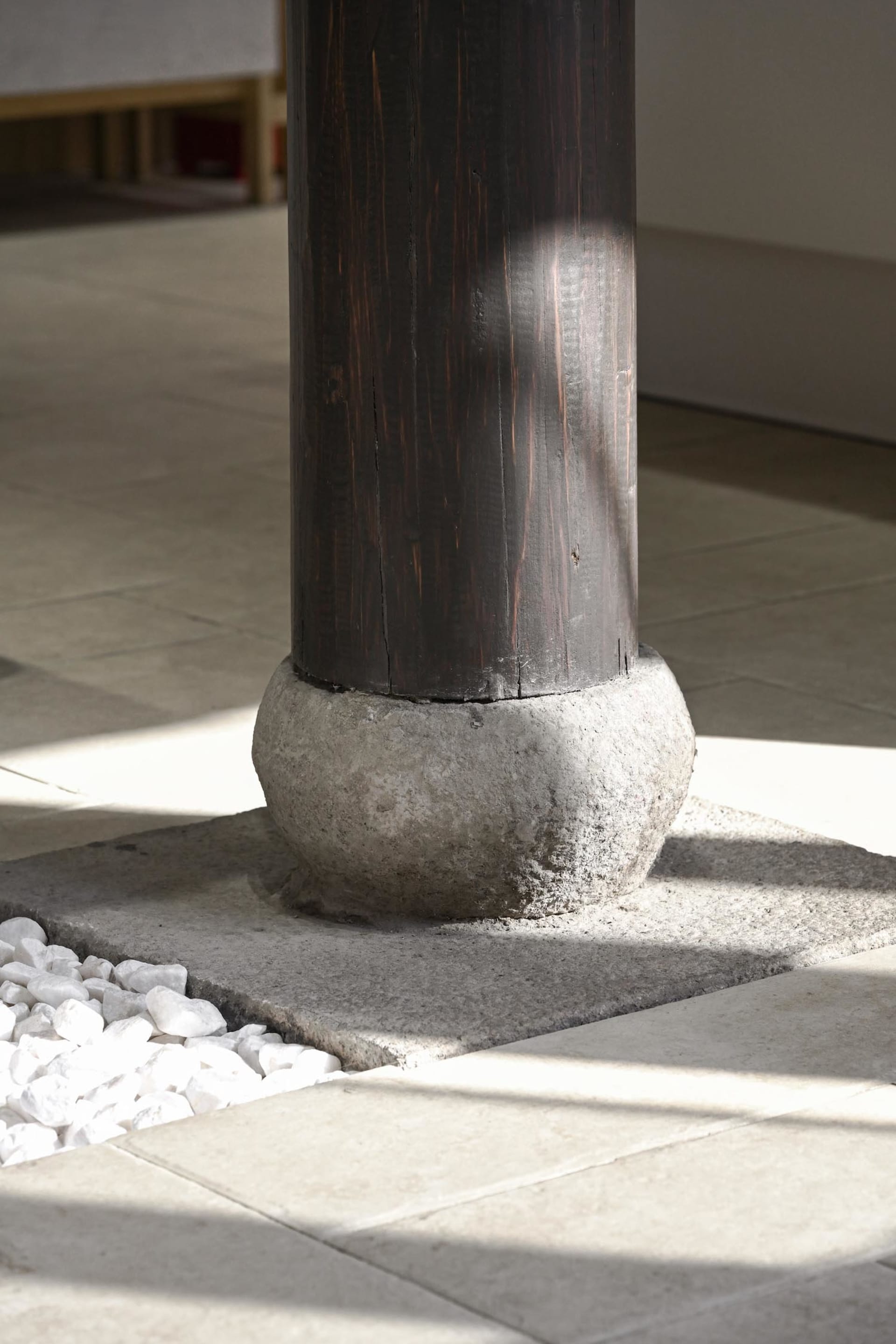 A dark wooden pillar base in a modern interior lobby setting.