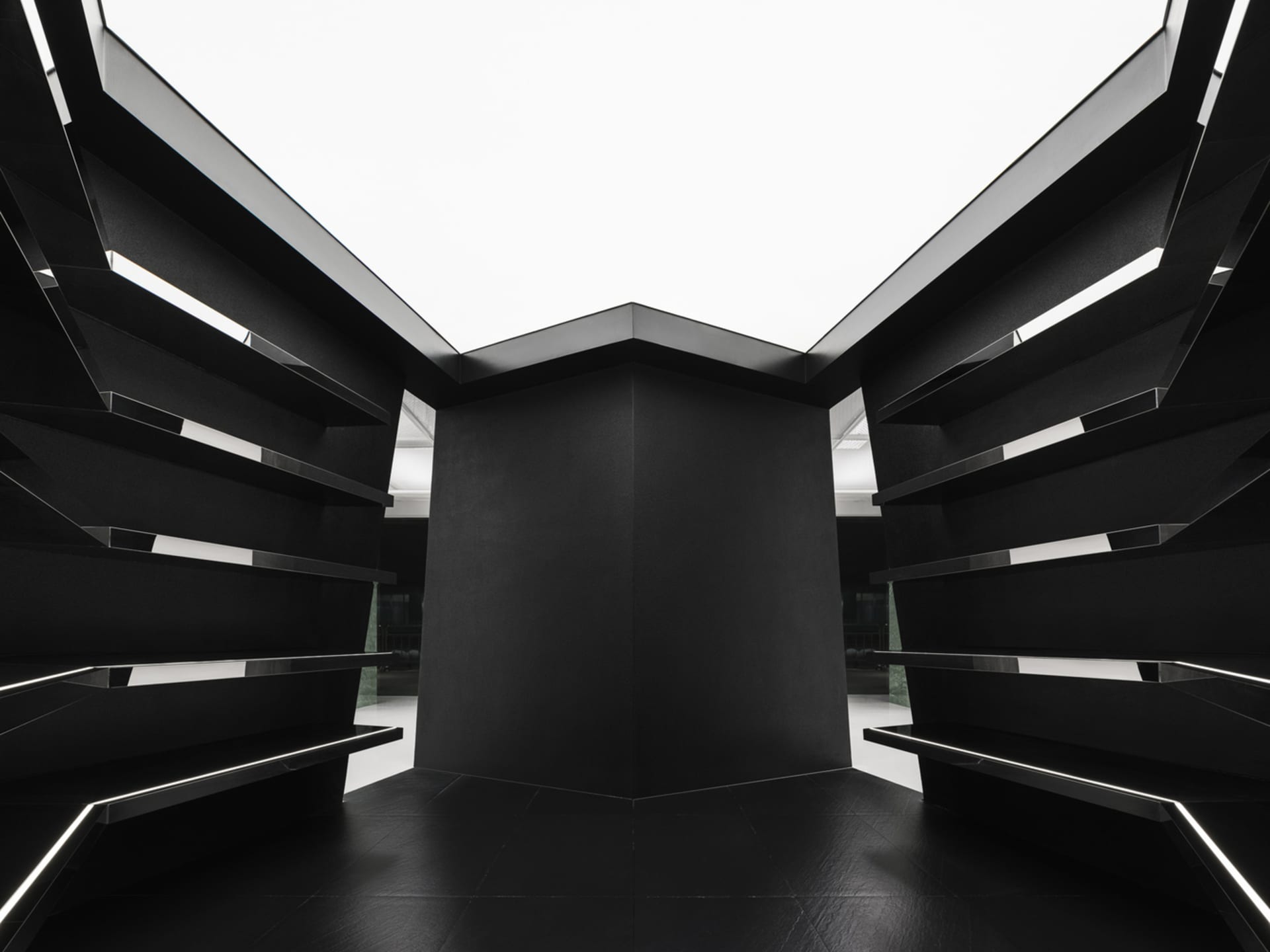 An empty black and white indoor room with geometric shapes and a tall, central structure.