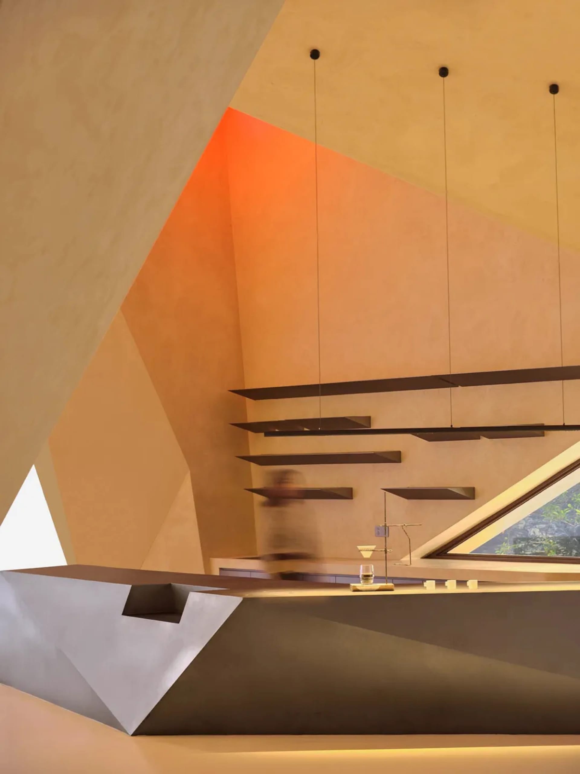 A modern interior design space featuring a concrete bar with geometric shelves and metal accents.