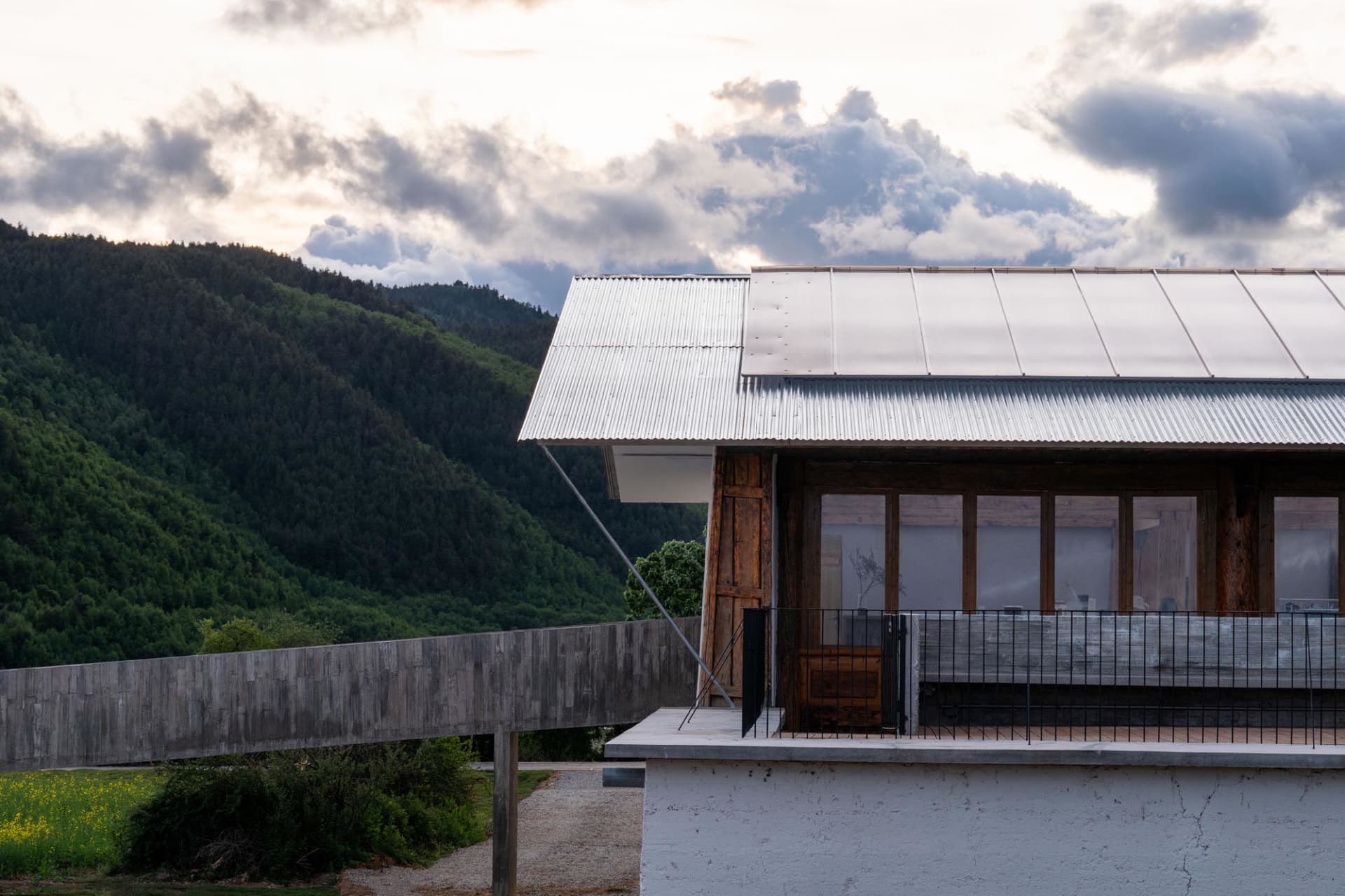 A modern residential exterior featuring a corrugated metal roof and a concrete foundation.