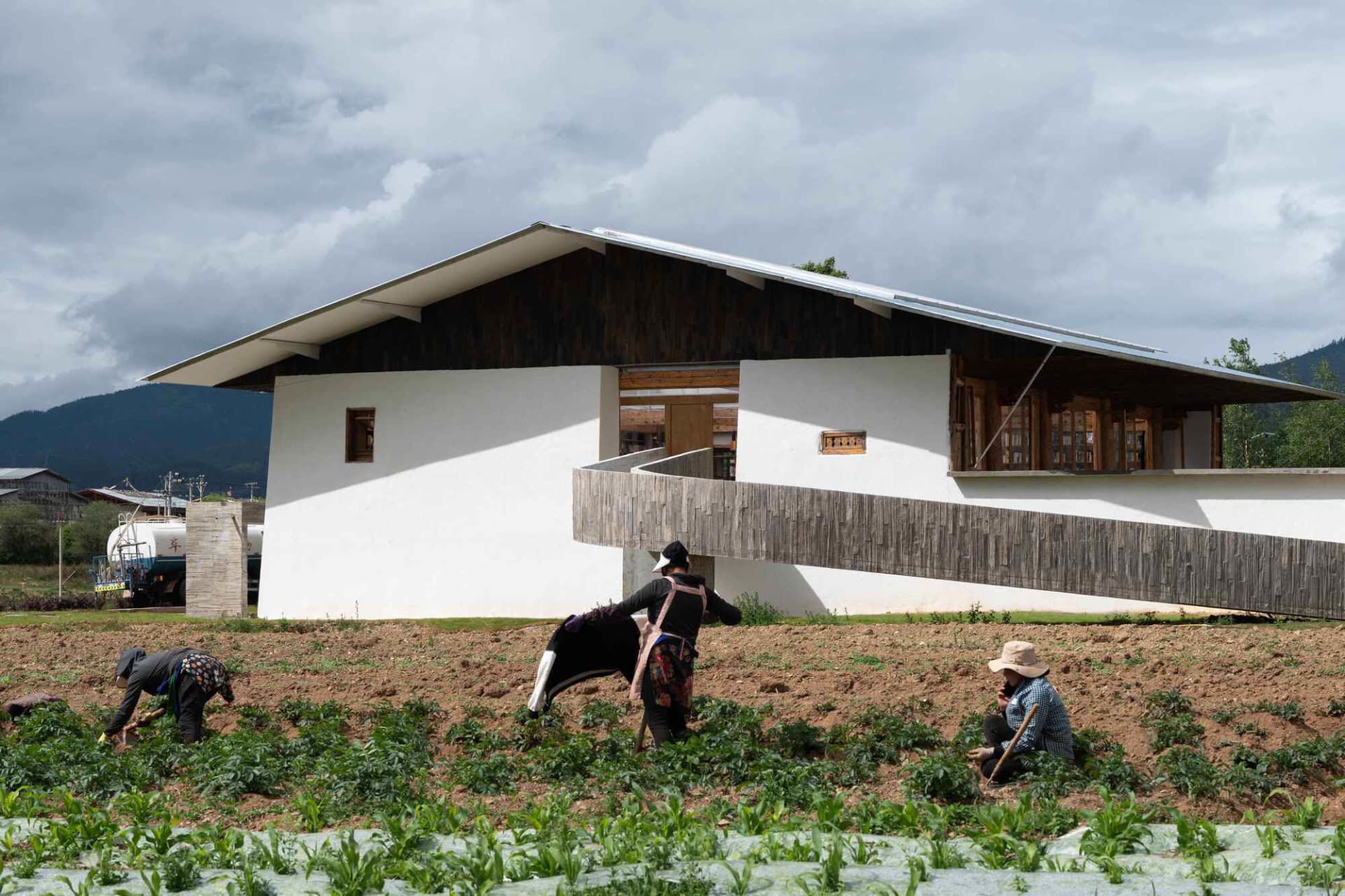 一棟白色住宅建築,搭配木質外牆與寬敞陽台。