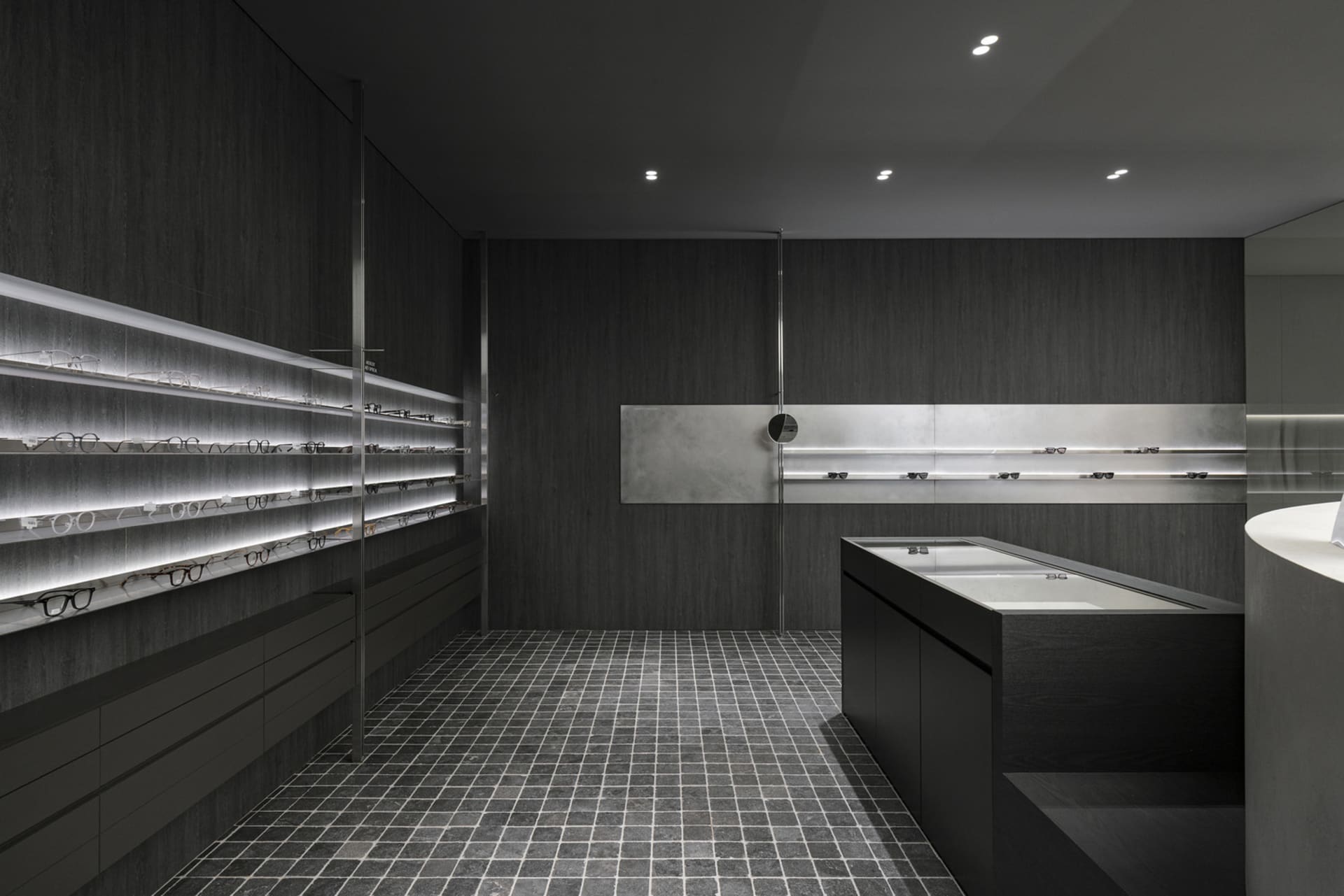 Minimalist eyewear store display with dark wood and glass materials