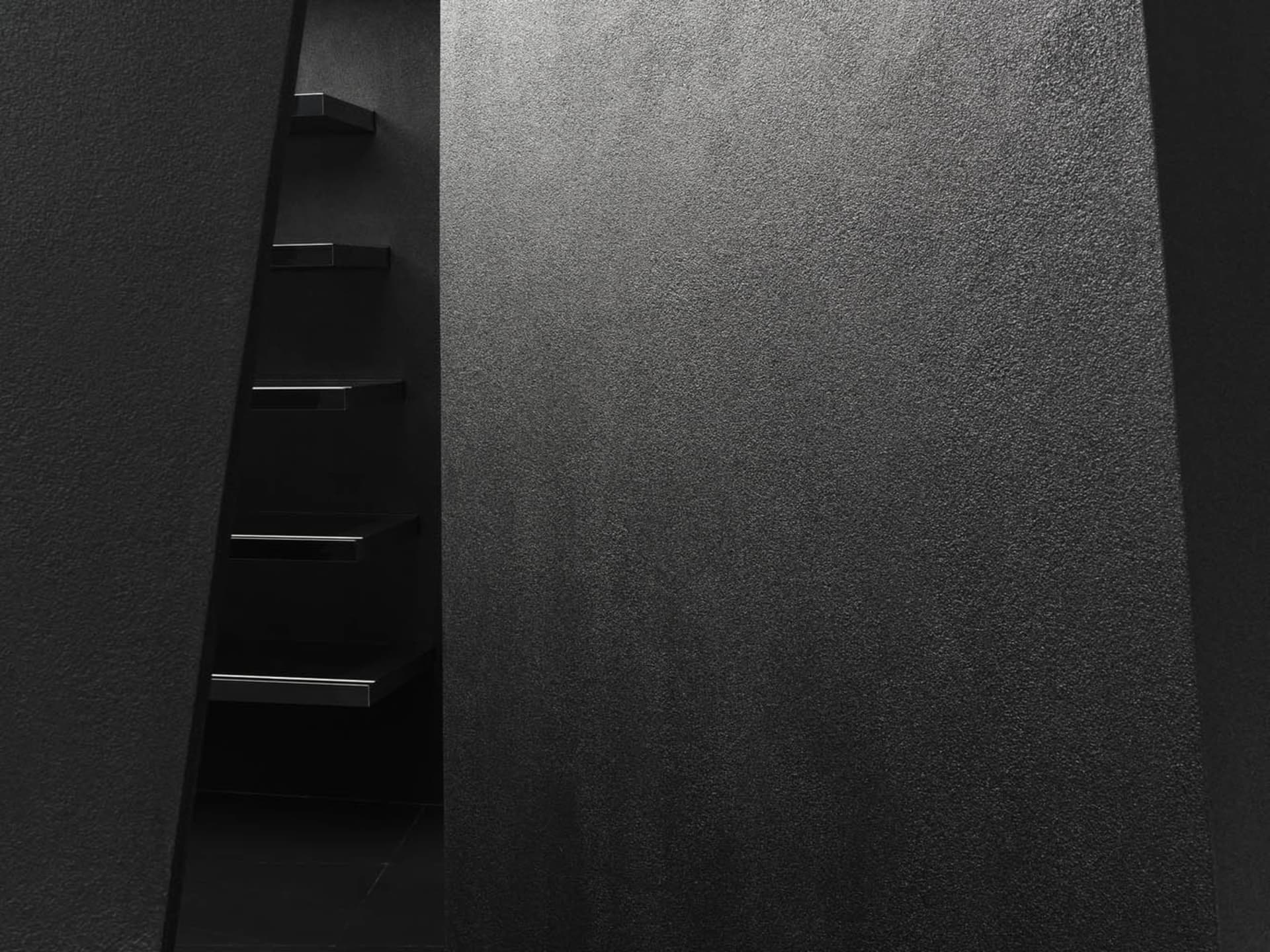 A minimalist staircase made of metal against a textured wall.