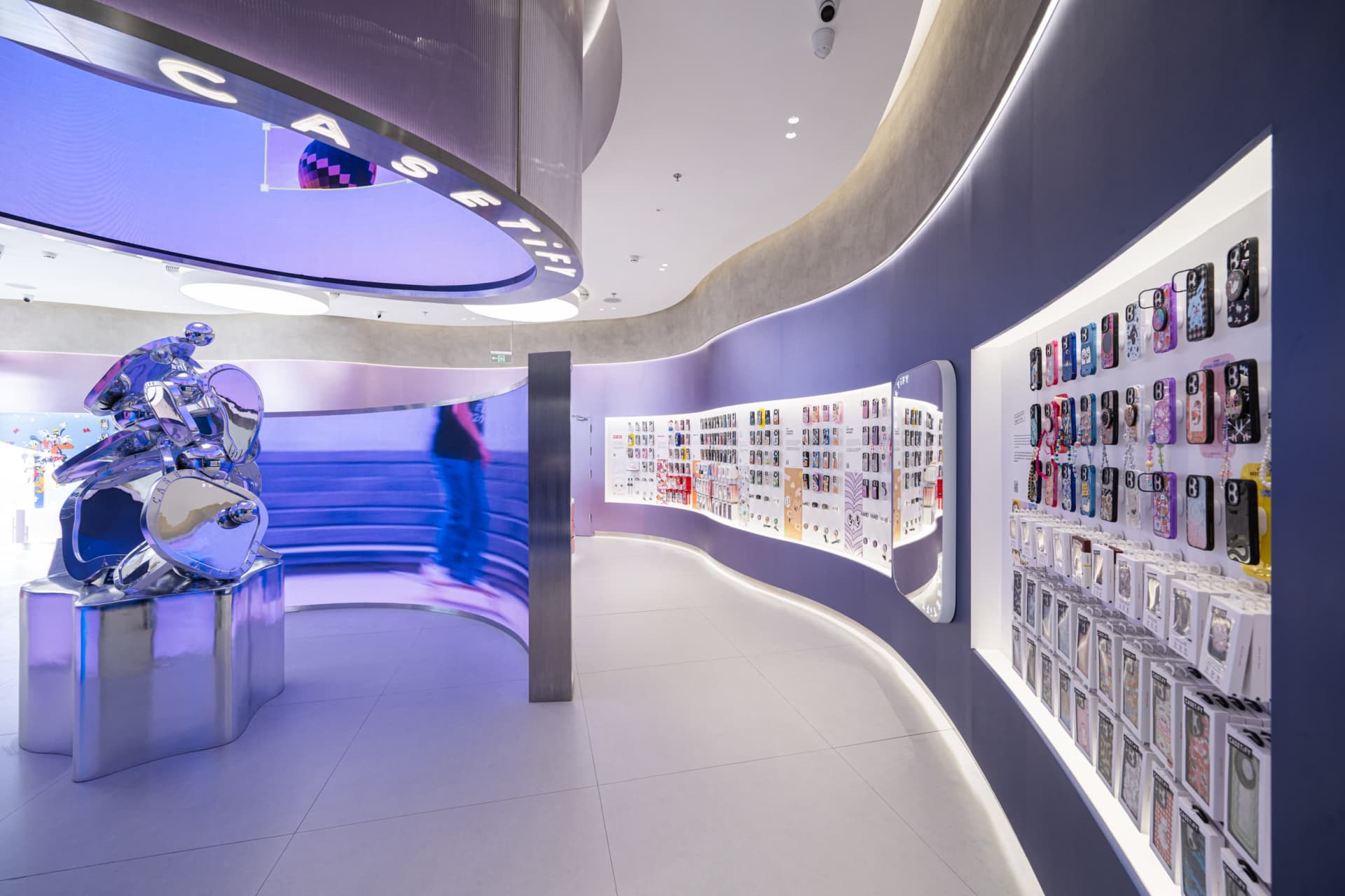 A modern retail store featuring a digital screen and metallic elements, surrounded by various mobile accessories.