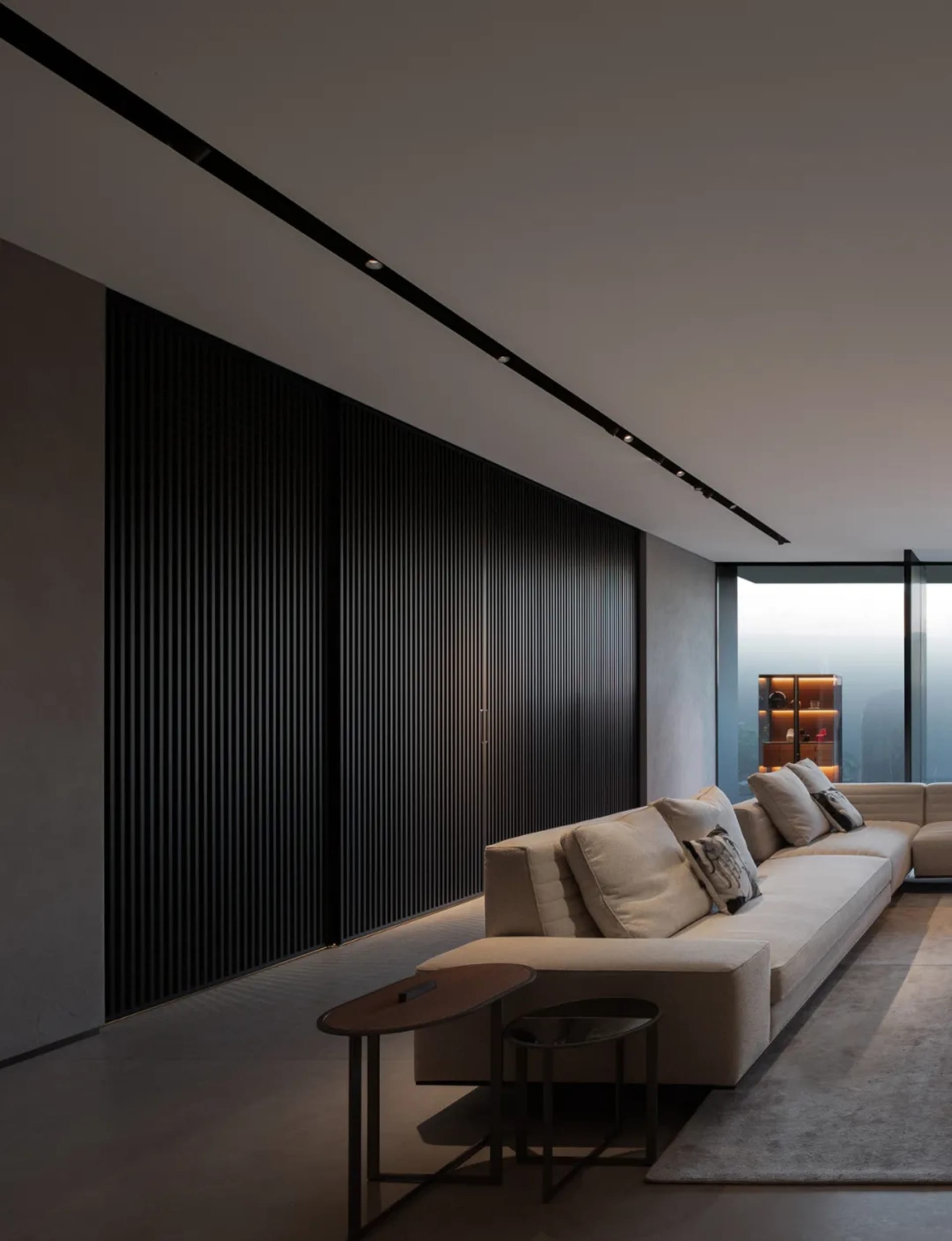 Modern living room featuring a beige sofa, concrete flooring, and large windows.