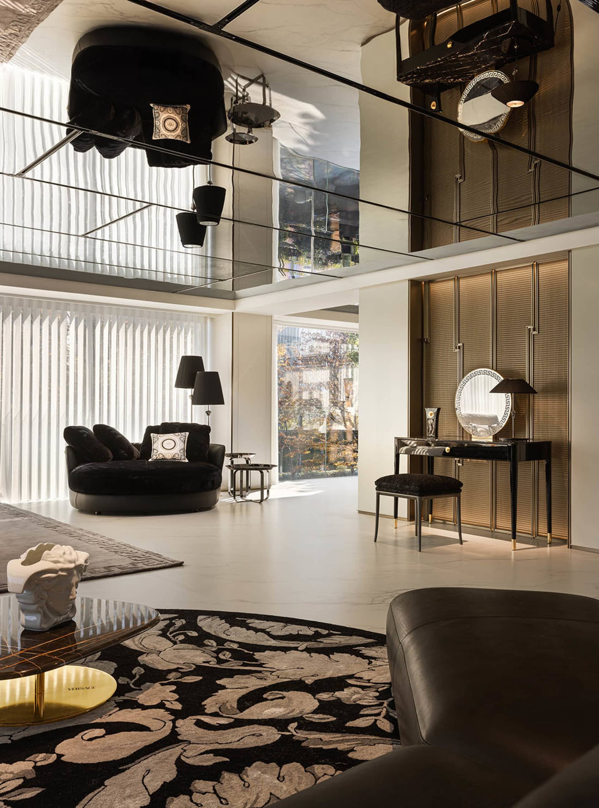 A modern living room featuring a round black sofa, a patterned rug, and a marble floor.