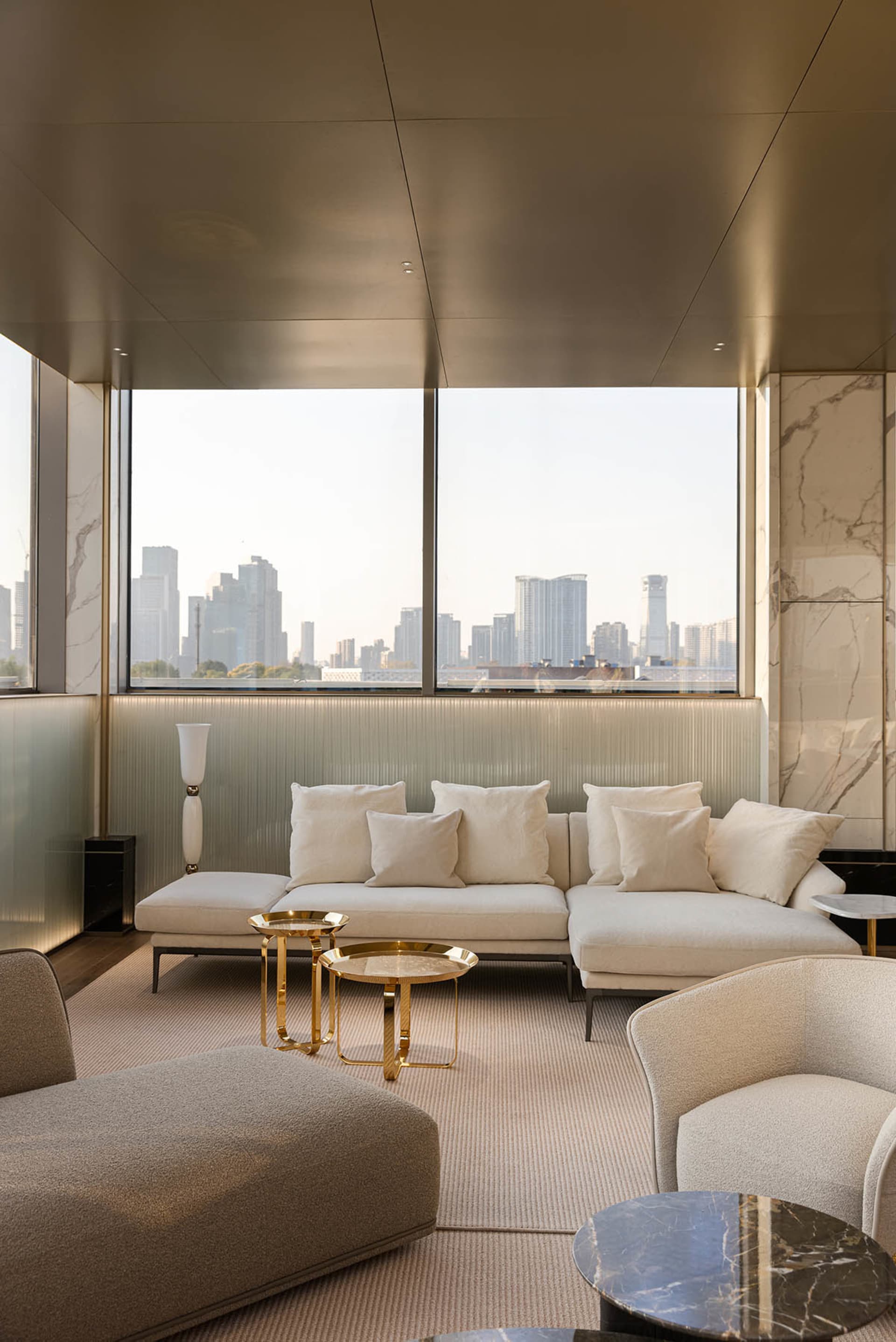 A contemporary living room featuring neutral-toned interiors, plush seating, and a panoramic city view.